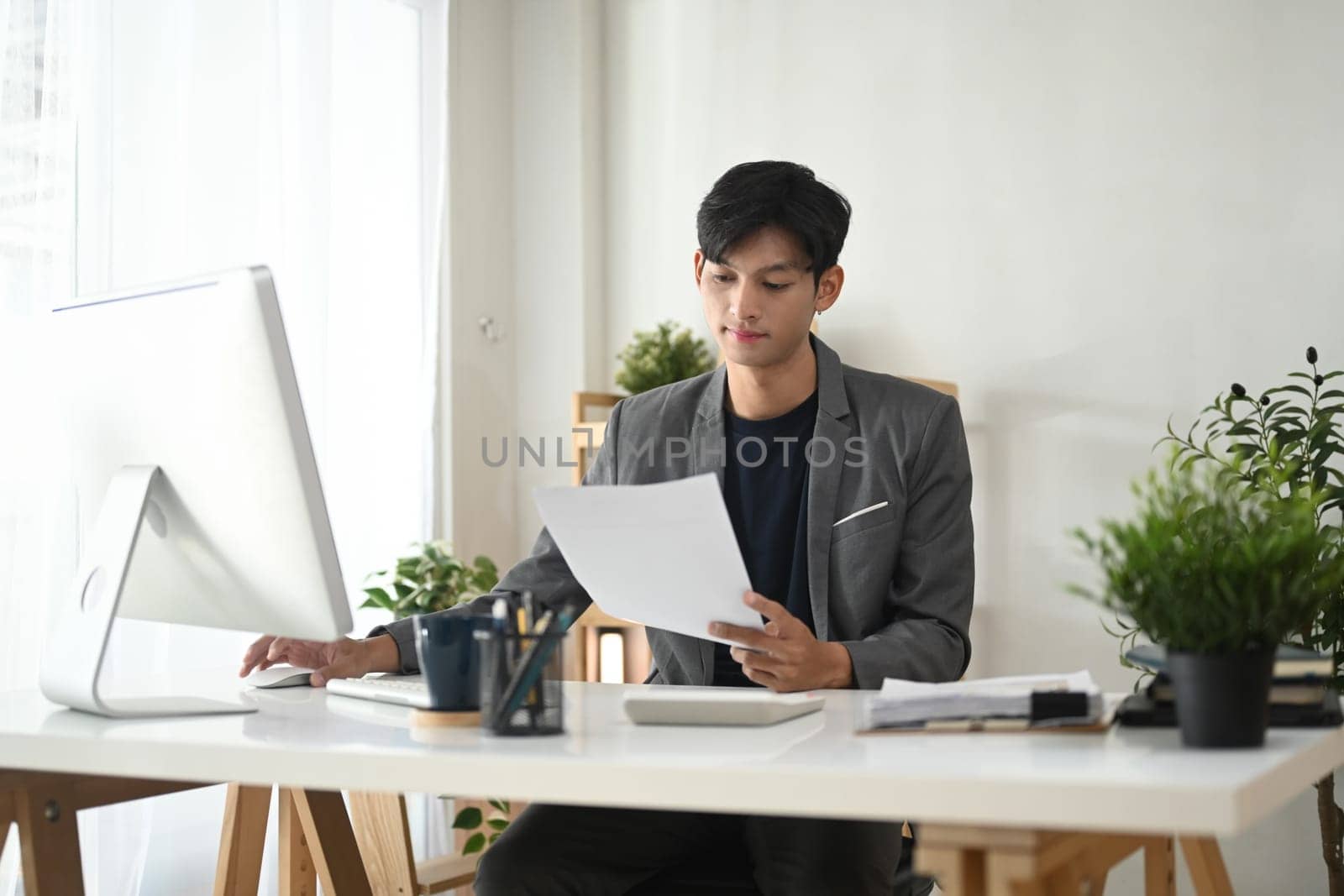Adult businessman in suit analyzing reports in a modern office space.