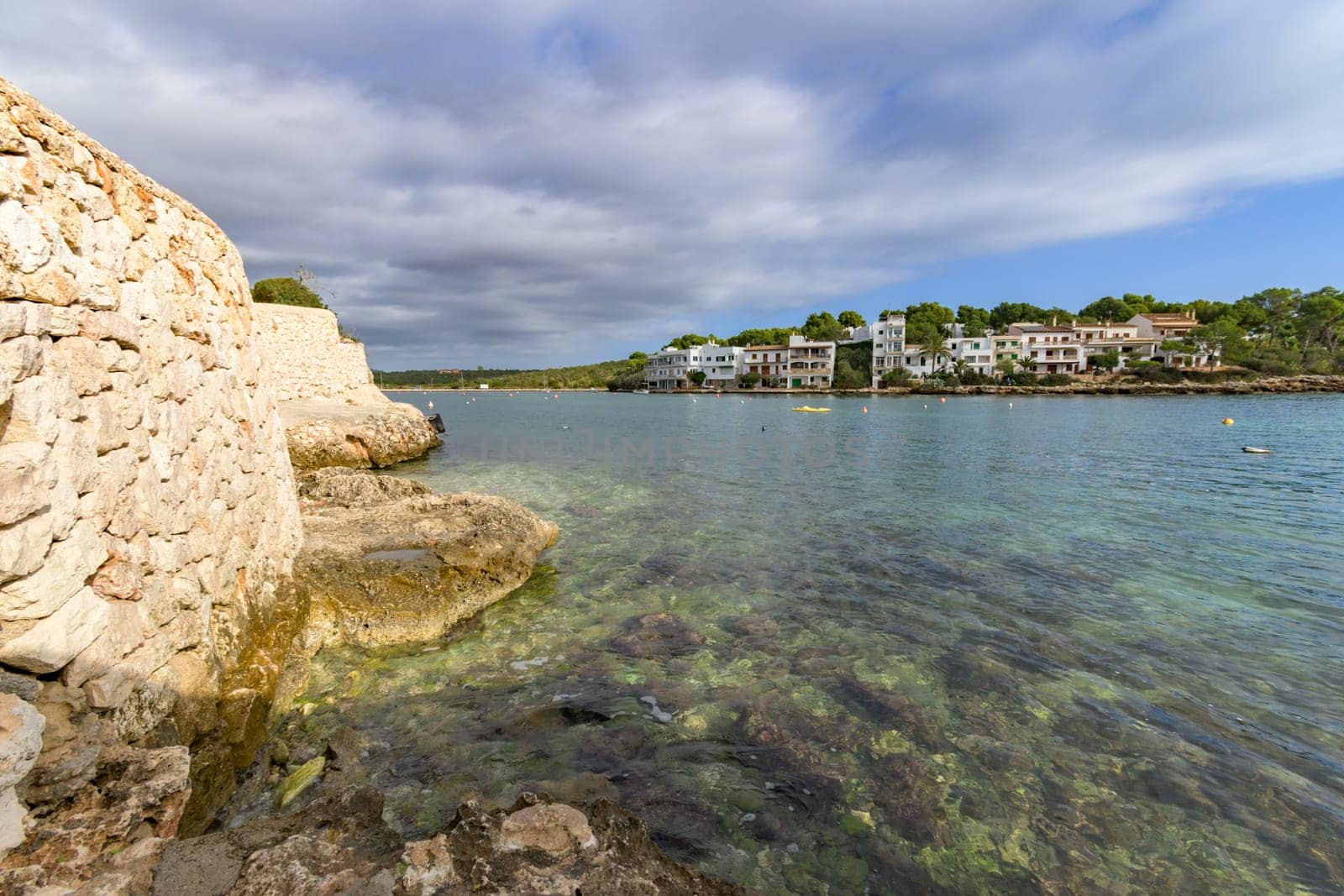 Peaceful coastal scene with rocky shore and clear water under a cloudy sky, porto petro, mallorca balearic islands, spain,