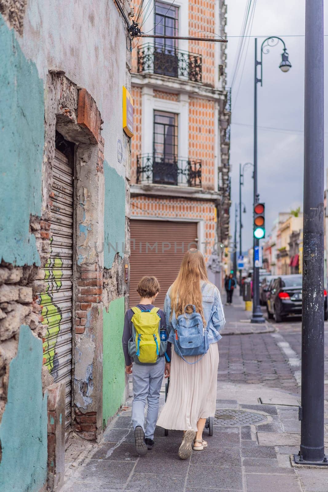 Mother tourist with her toddler and teenage sons walking through the colorful colonial streets of Puebla, Mexico. Travel, cultural exploration, and vibrant architecture concept.