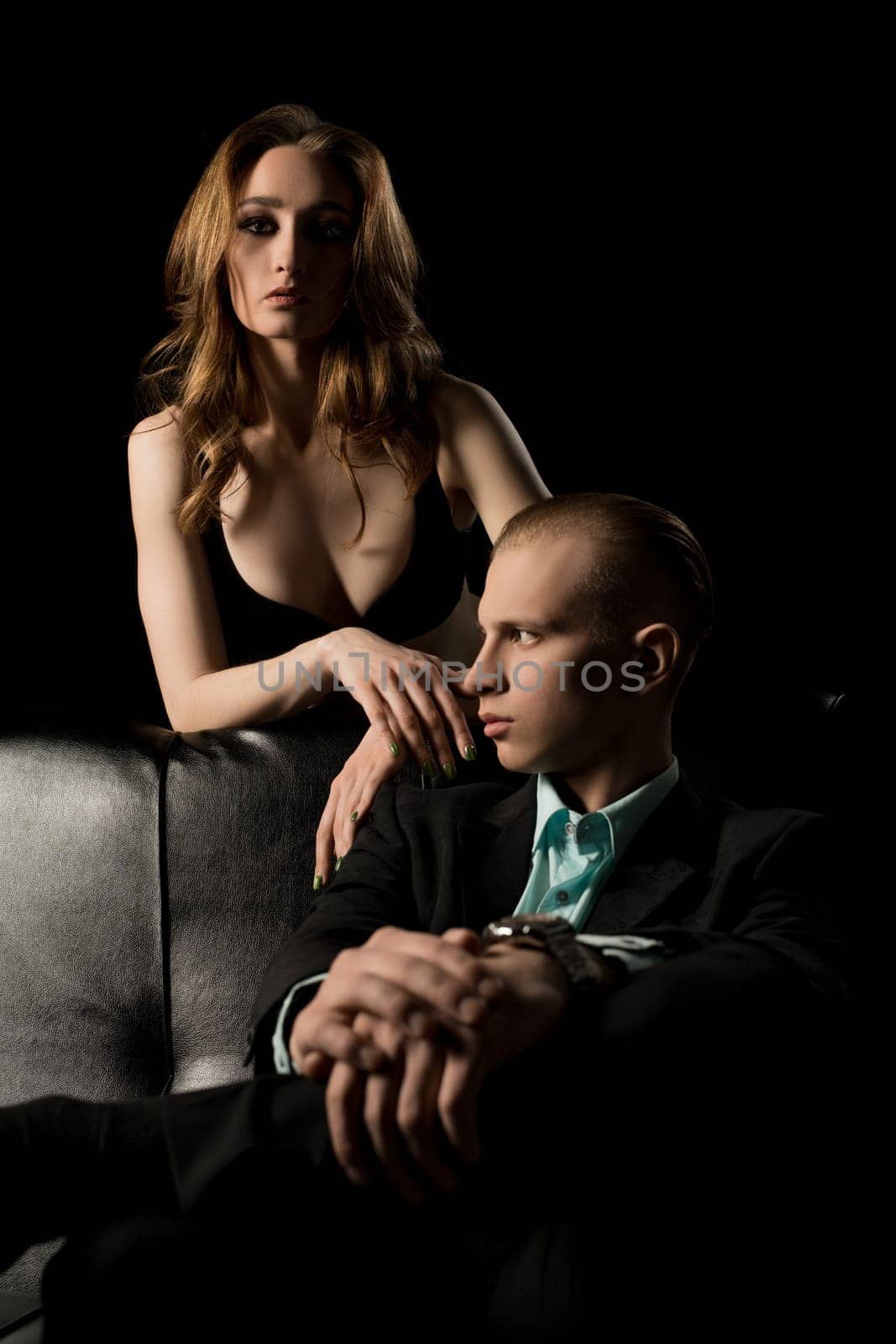 Gorgeous couple date shot on black leather sofa at night