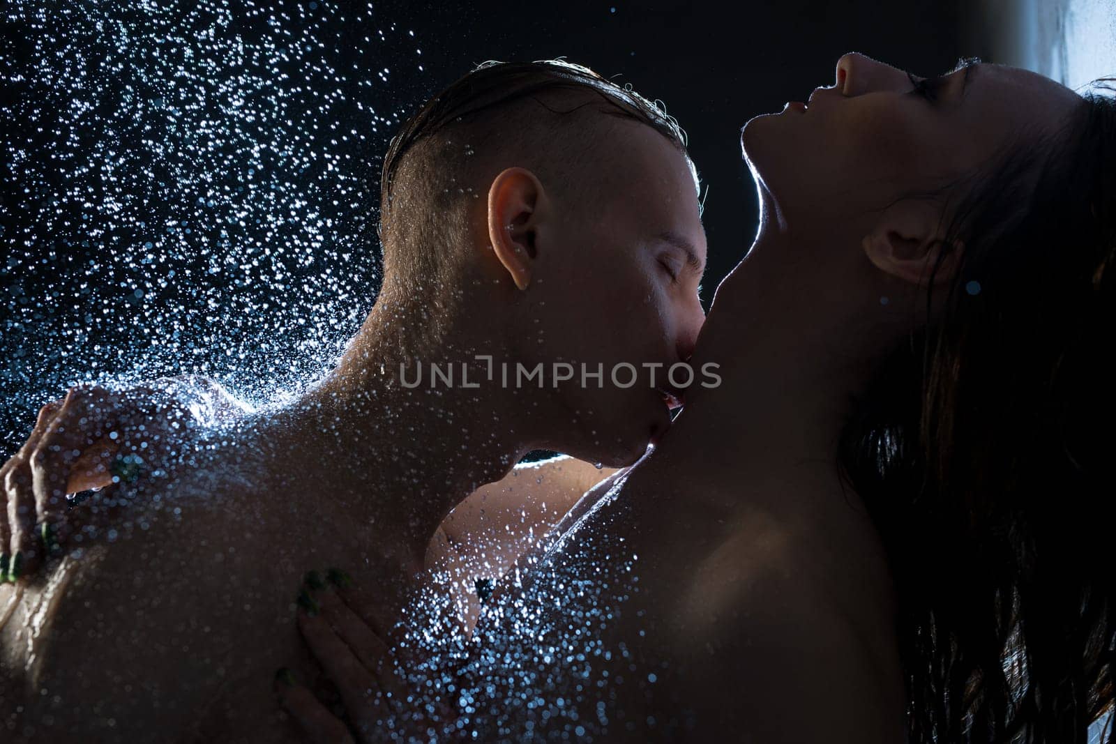 Nude couple embracing in dark shower cropped shot