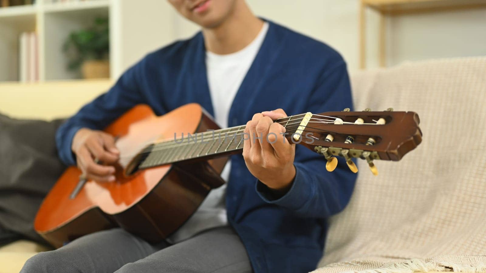 Young man enjoying guitar practice in cozy living room.