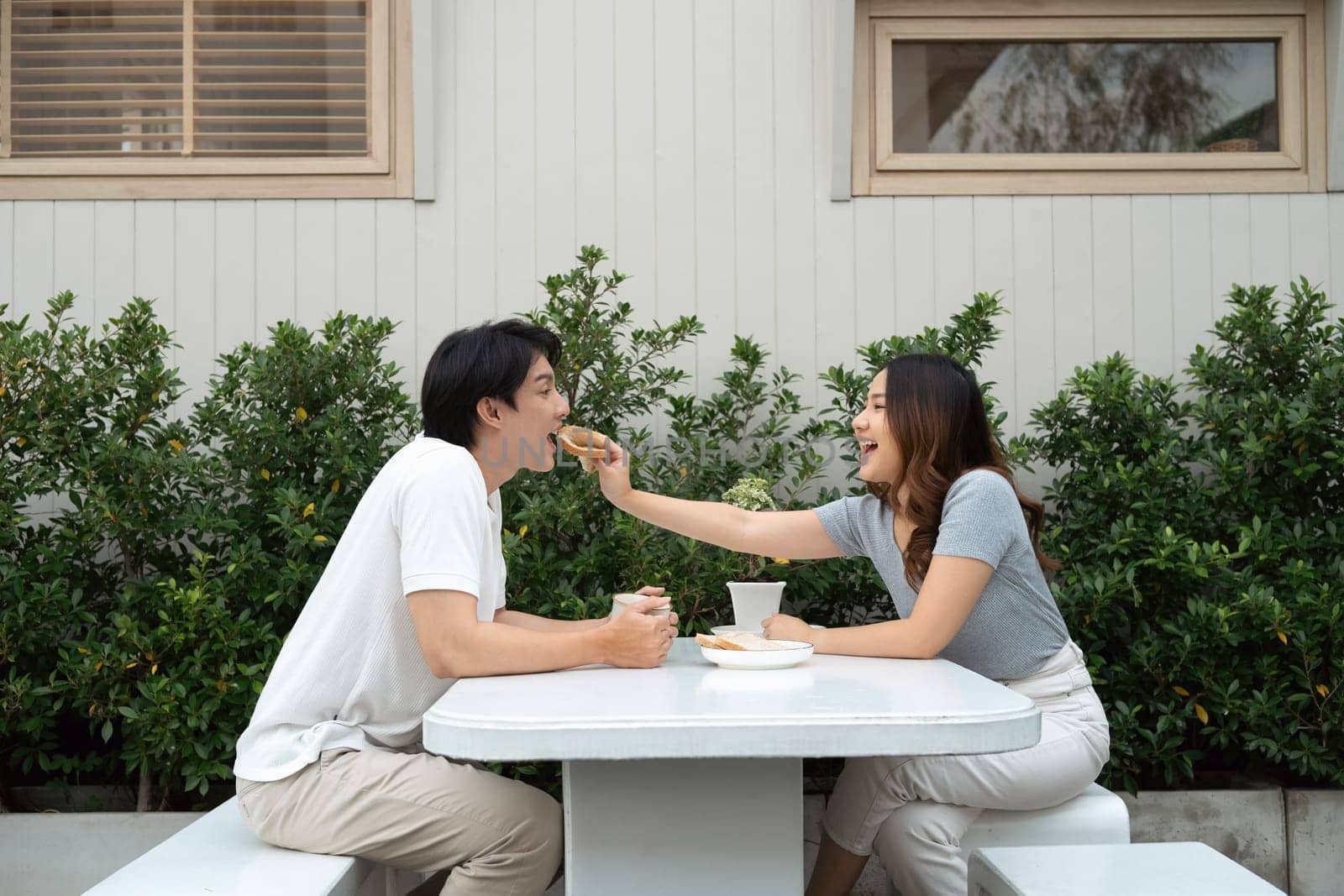 Loving young adult couple enjoying breakfast together in the garden.