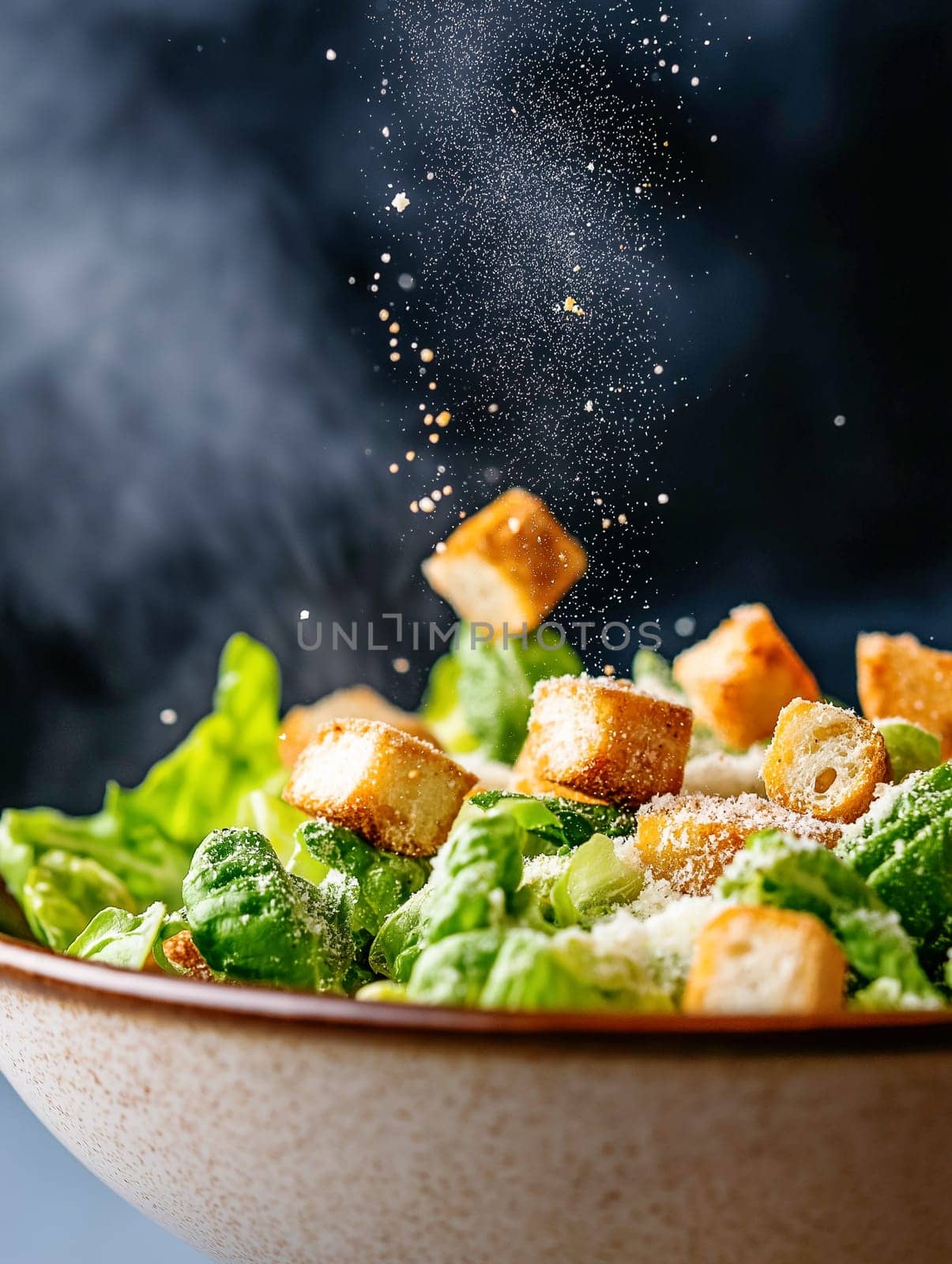 A bowl of salad with croutons and cheese sprinkled on top. The salad is served in a white bowl and the croutons are scattered throughout the salad
