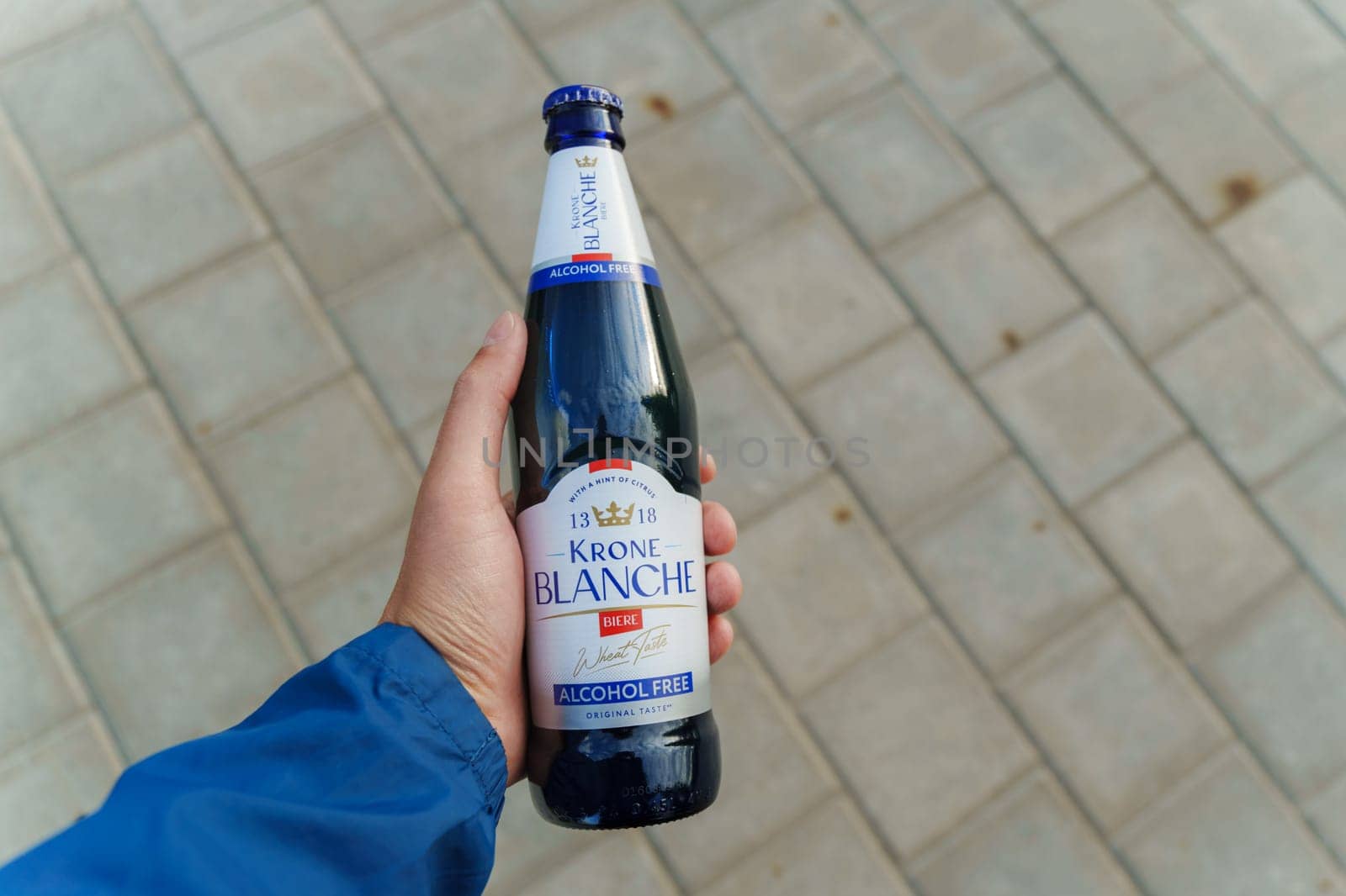 Tyumen, Russia-August 10, 2024: A person holding a bottle of alcohol-free Krone Blanche on a swing in a park during daylight