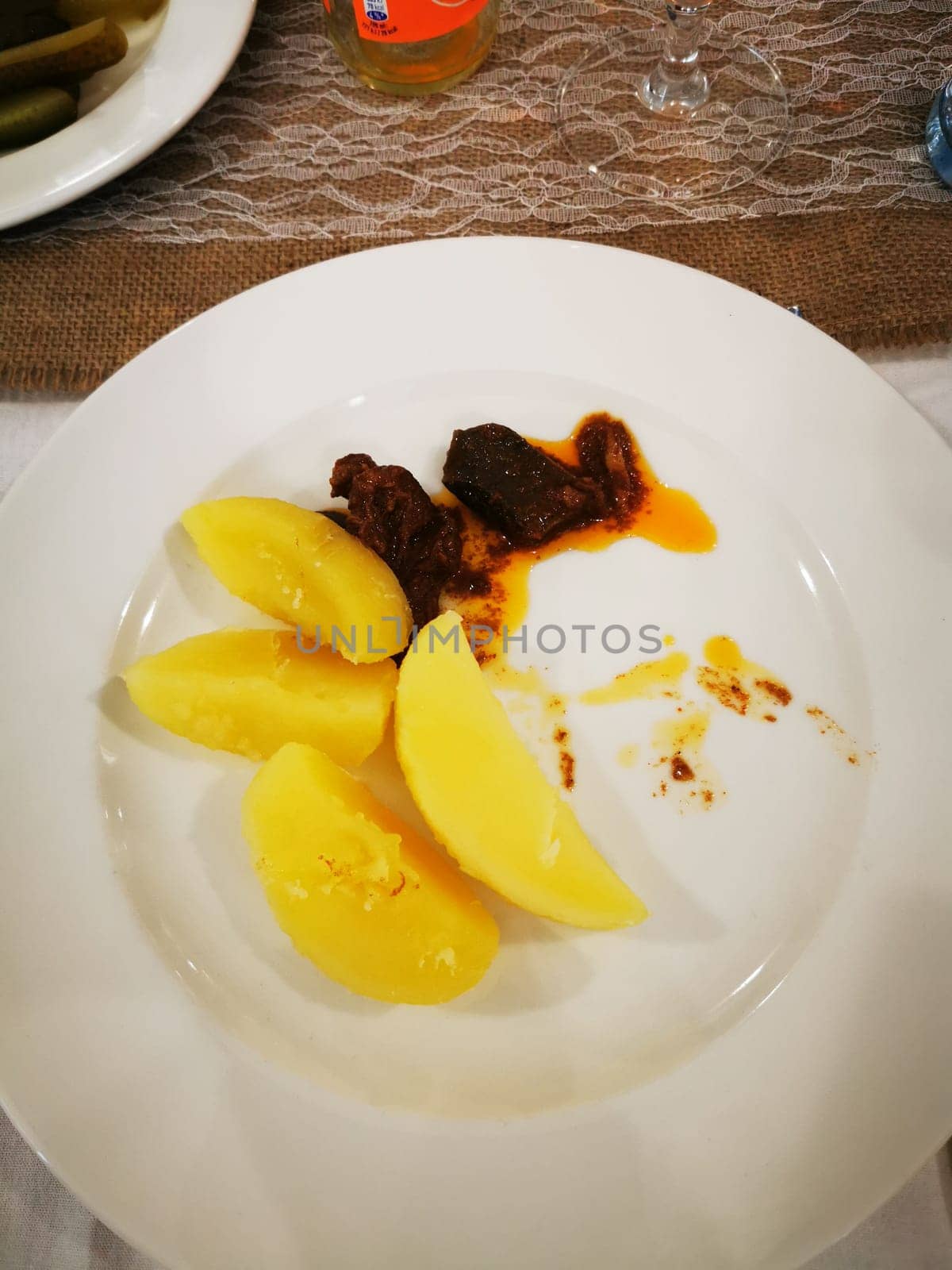 The plate showcases a portion of tender meat garnished with a spicy sauce, alongside neatly arranged wedges of sweet potatoes, indicating a flavorful meal enjoyed.