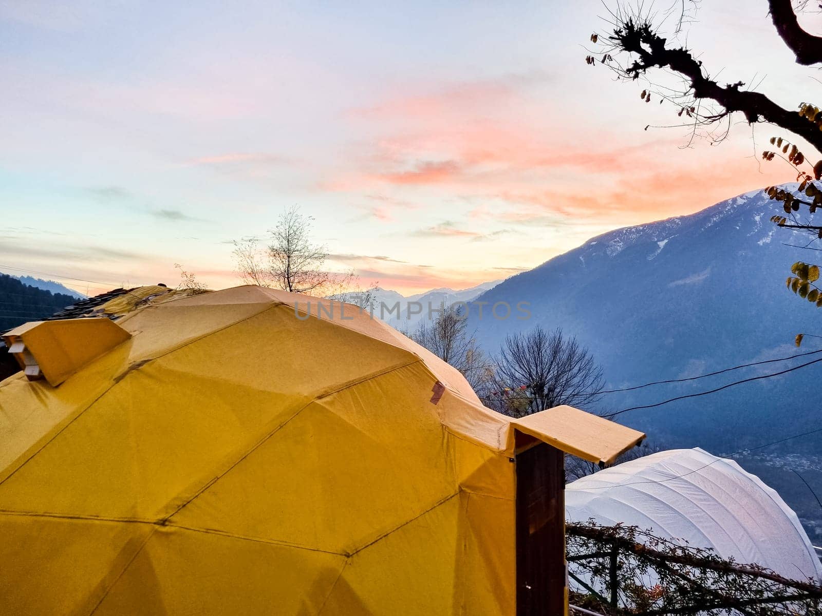 geodesic and swiss tents overlooking manali valley at sunset at a popular glamping spot near hampta village for eco freindly and comfortable adventure stays