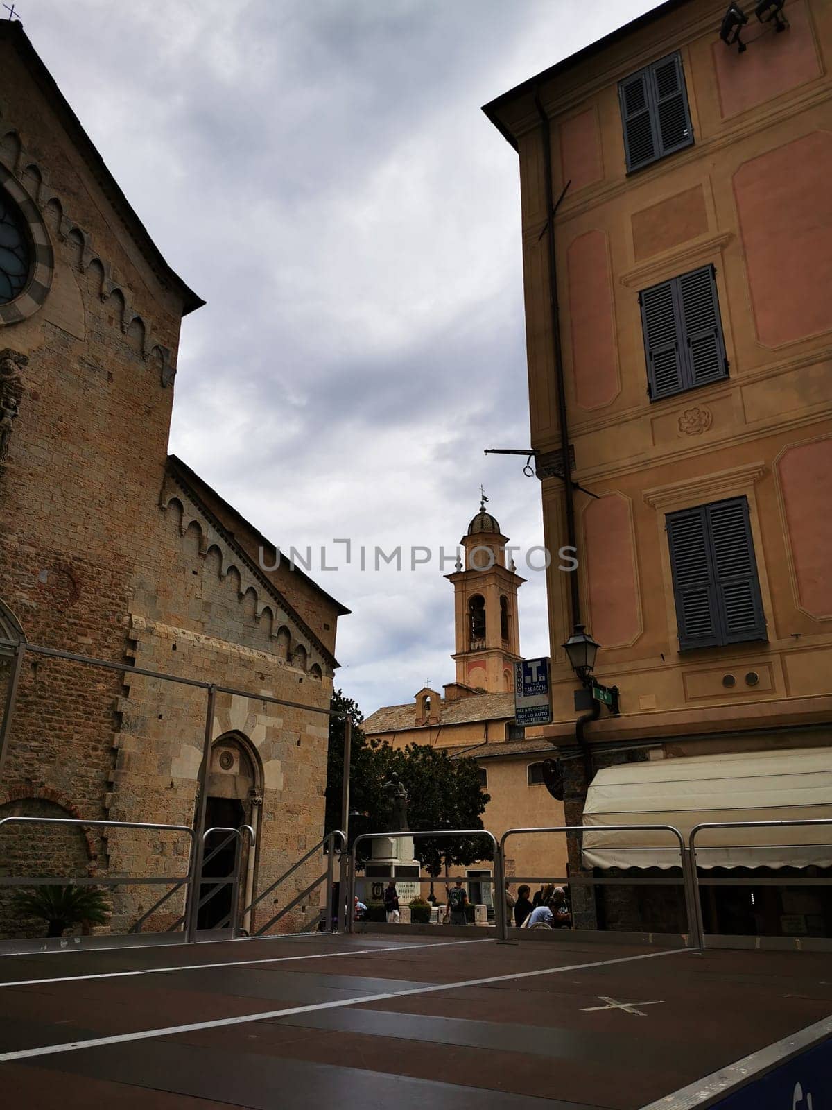 Strolling through a historic town, the view captures charming architecture and a church tower framed by buildings under an overcast sky in the afternoon.
