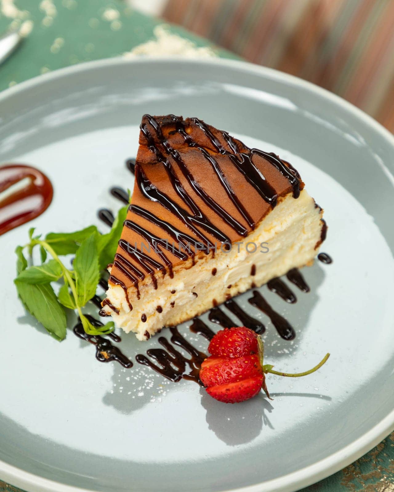 Slice of cheesecake decorated with chocolate sauce and strawberries, served on a plate