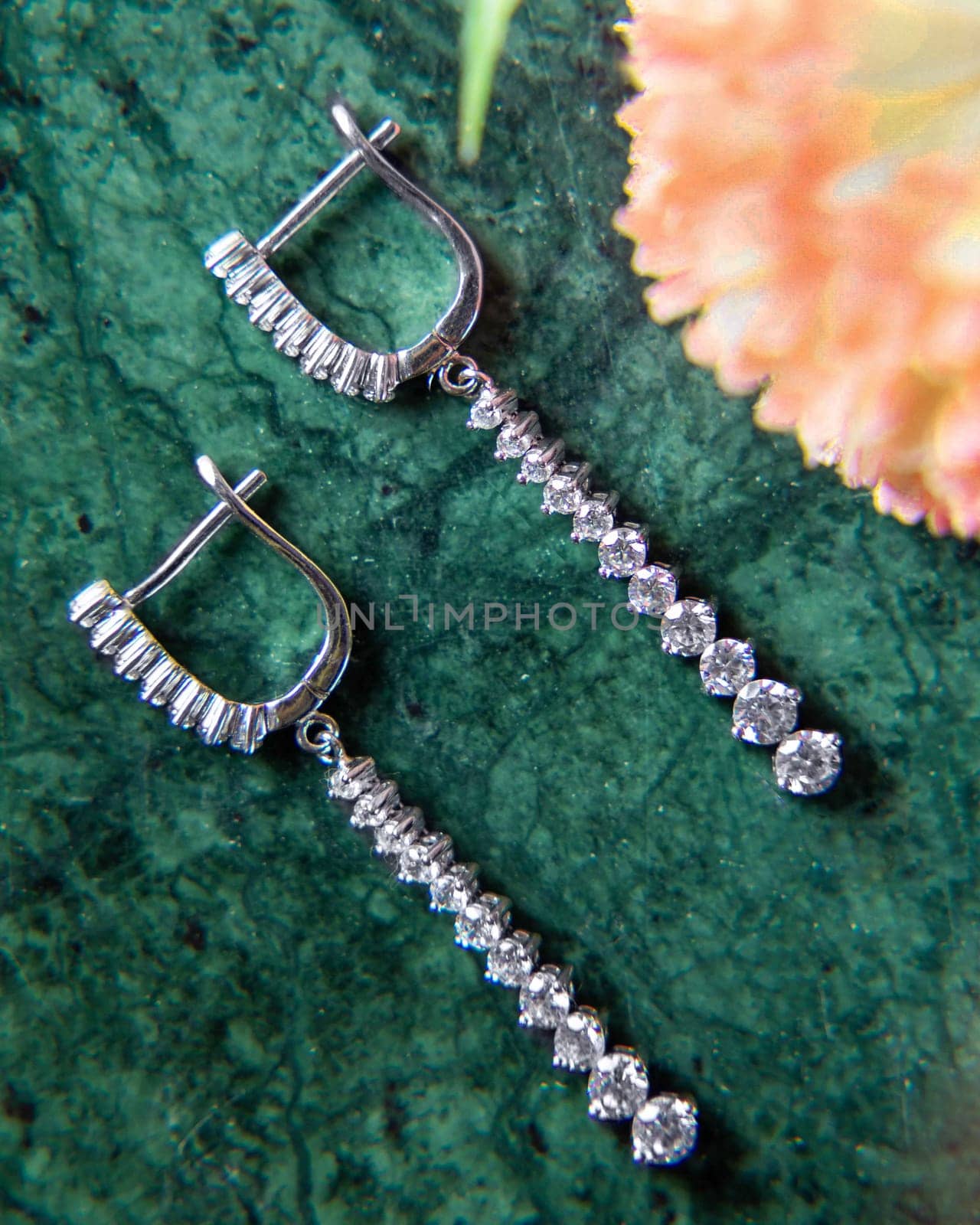 Pair of white gold diamond earrings lying on green malachite stone