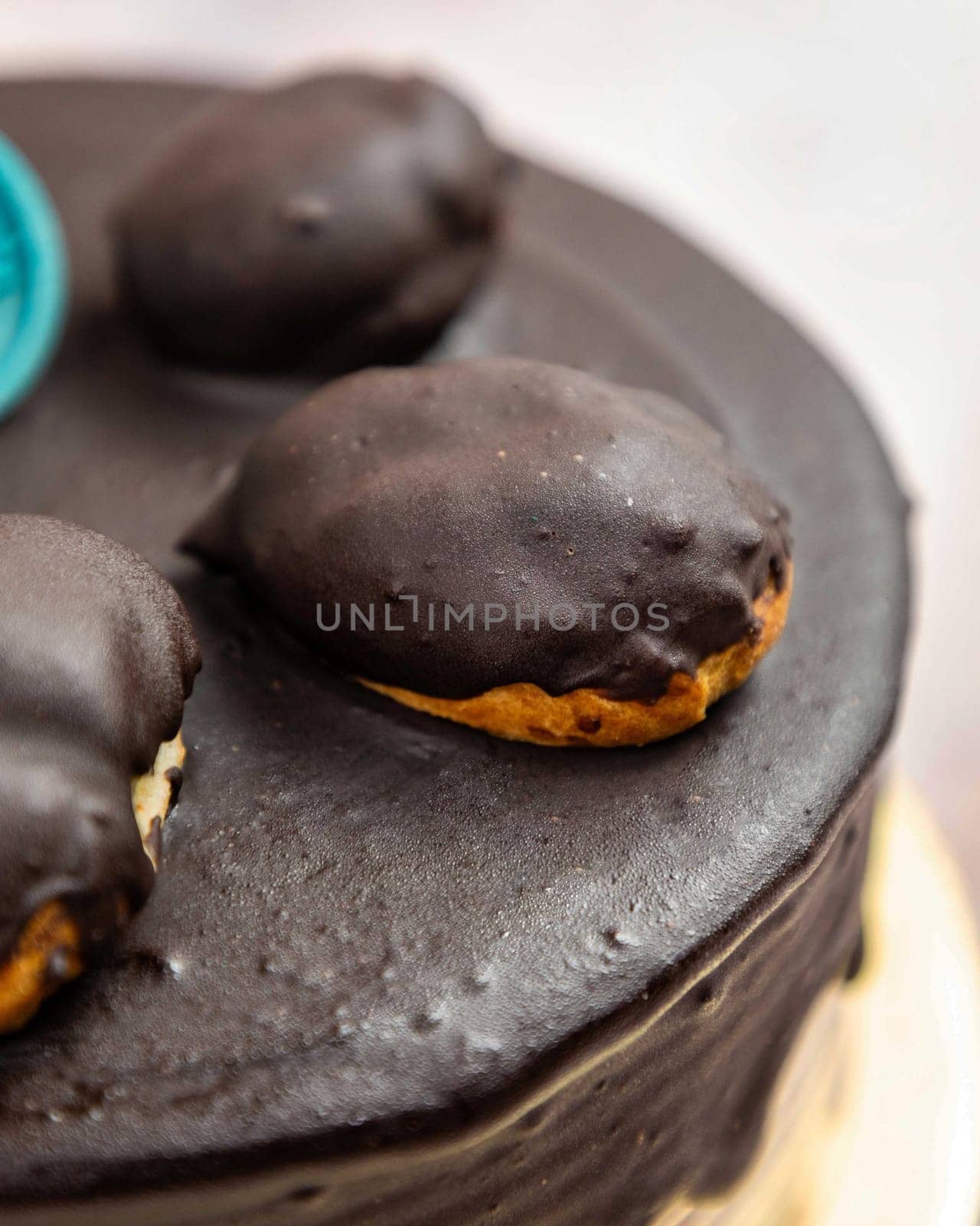 Delicious homemade chocolate cake with chocolate glaze and eclairs on the top, standing on a plate