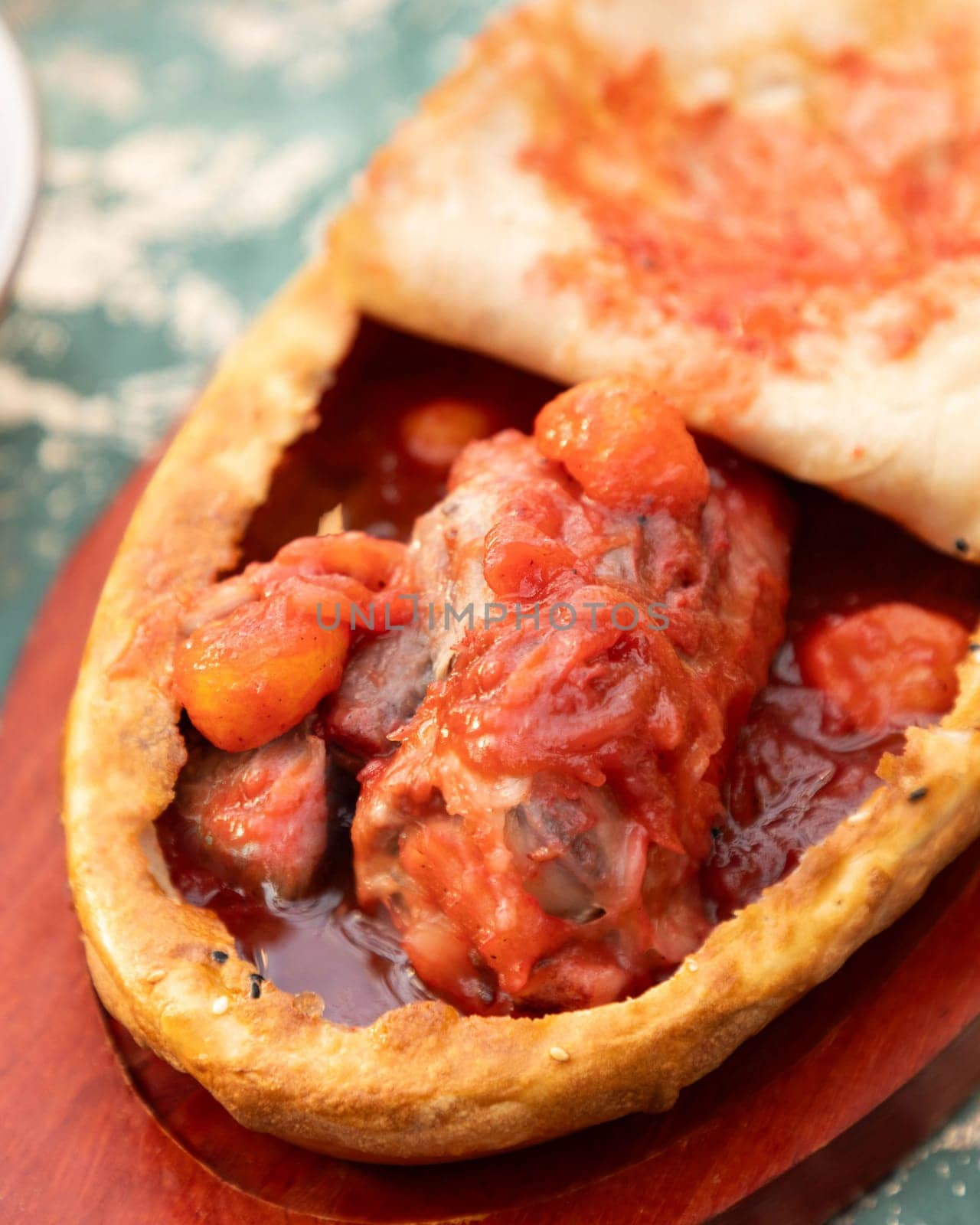 Traditional tajik meat dish with vegetables and tomato sauce baked in bread served on wooden board