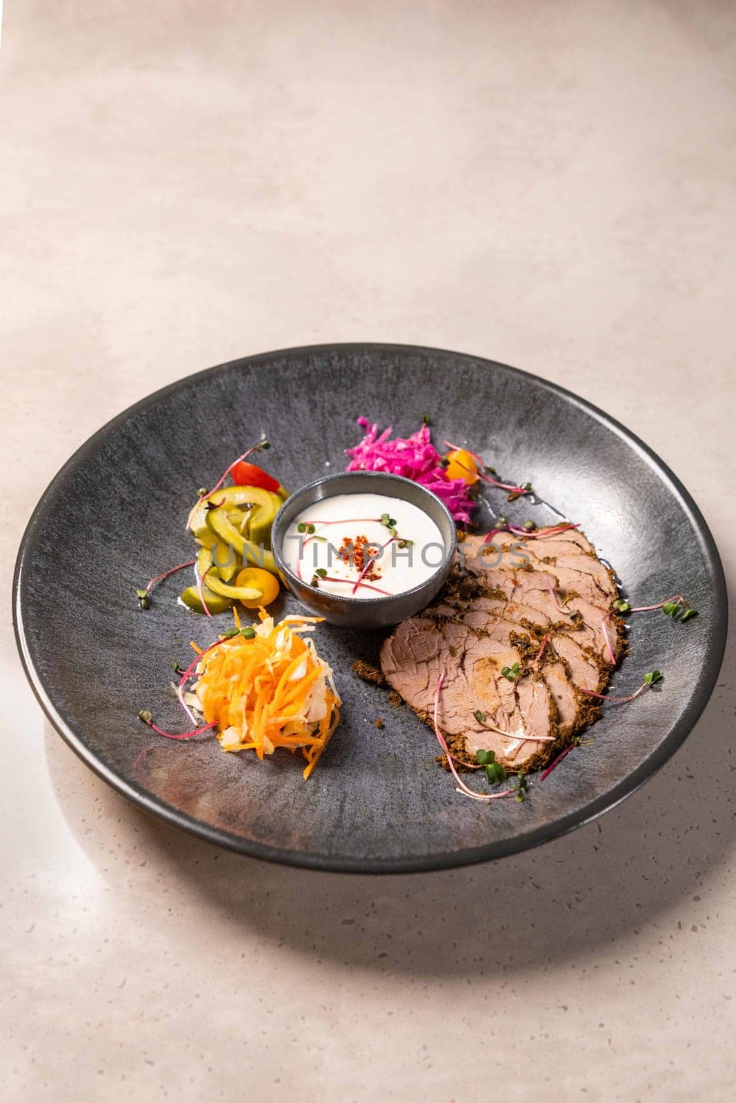 Sliced roast beef with herbs and spices served on a plate with pickled vegetables and a creamy sauce, creating a visually appealing and flavorful culinary experience
