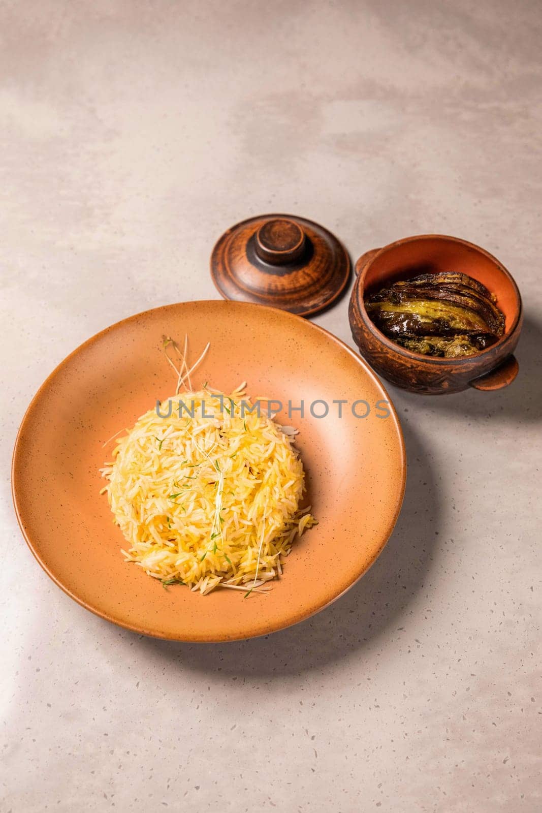Saffron rice with herbs served on a plate with a side dish of eggplant