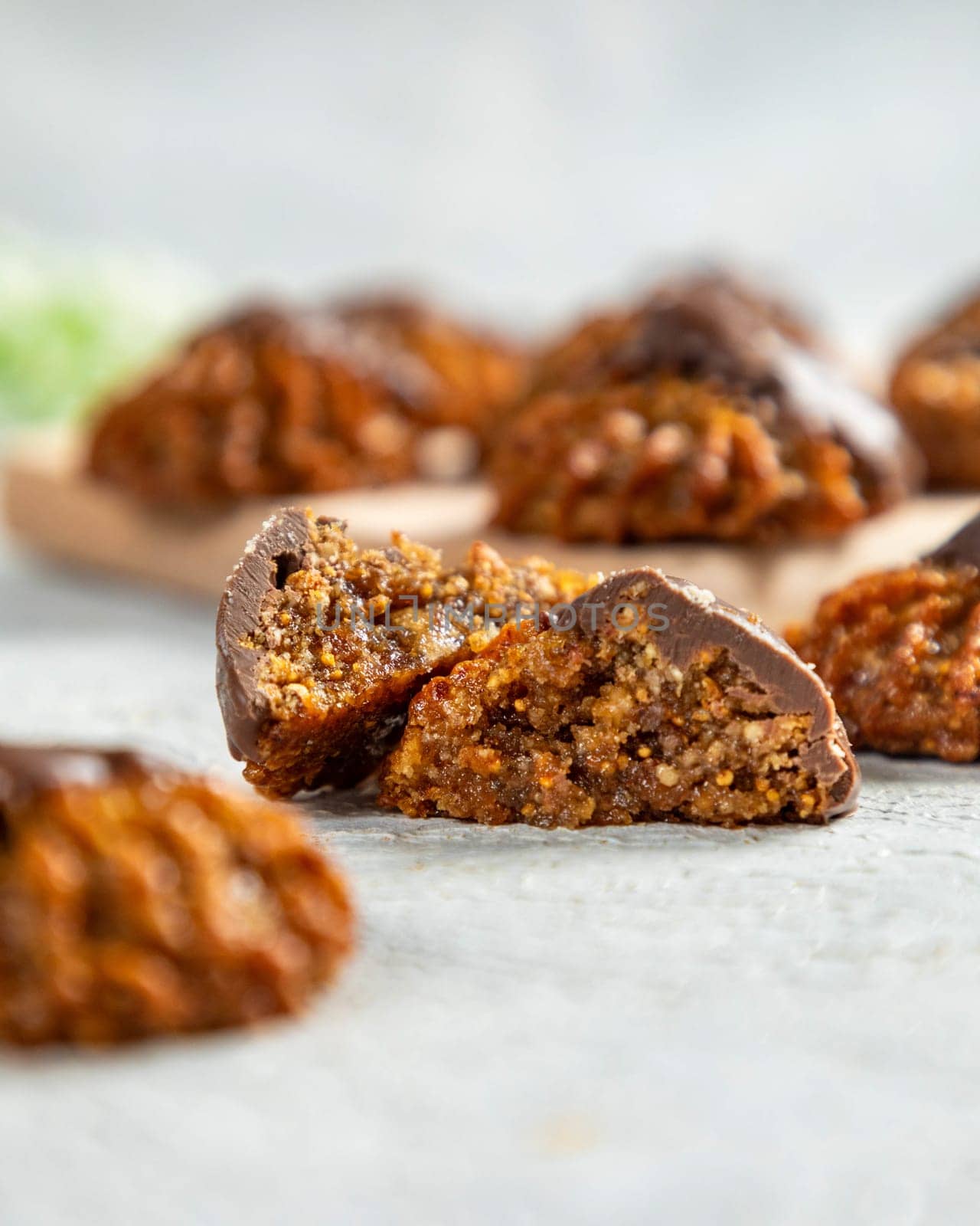 Delicious homemade fig and nut cookies covered in chocolate are broken in half revealing the filling