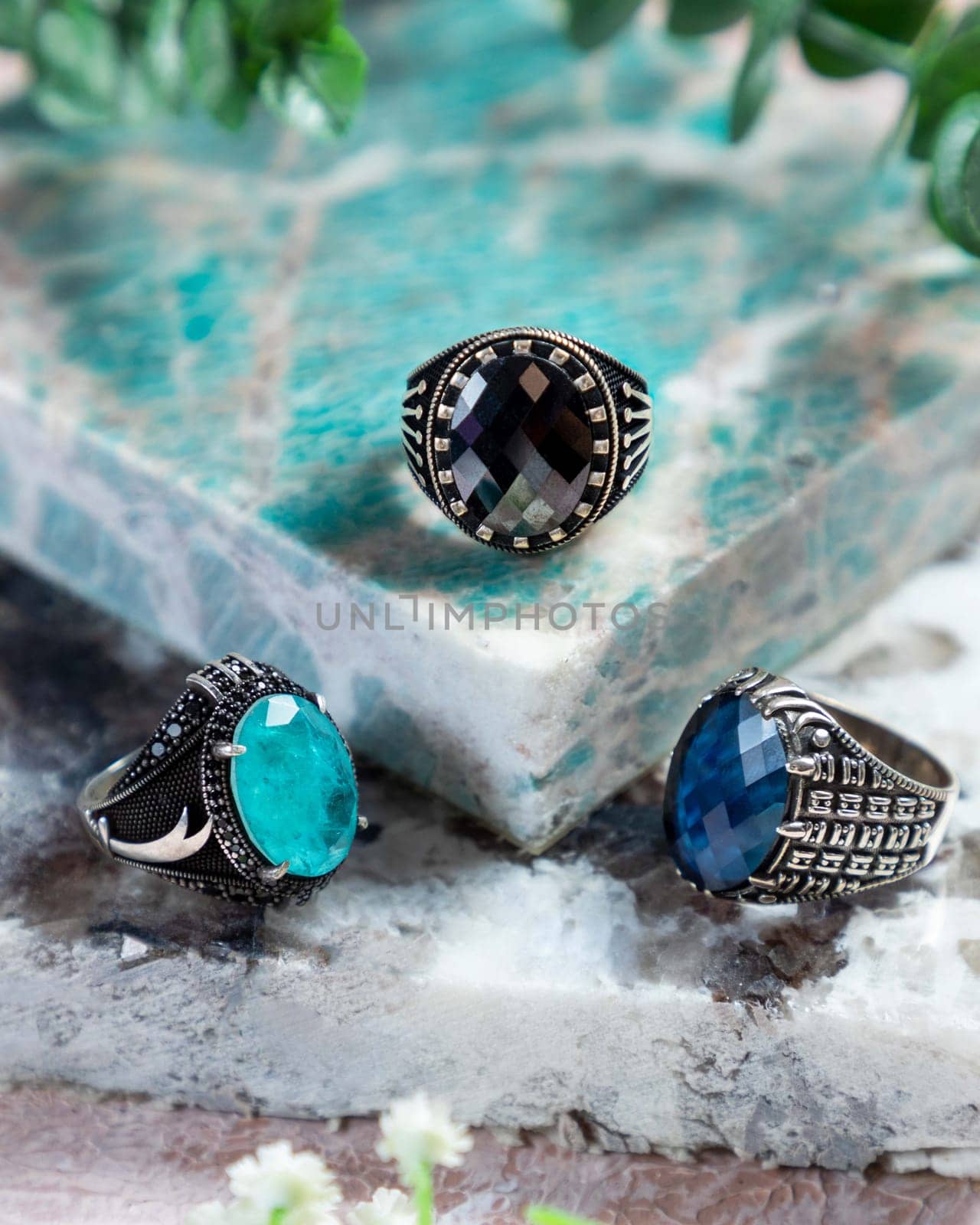 Silver men's rings with black, blue and green gemstones on a turquoise background