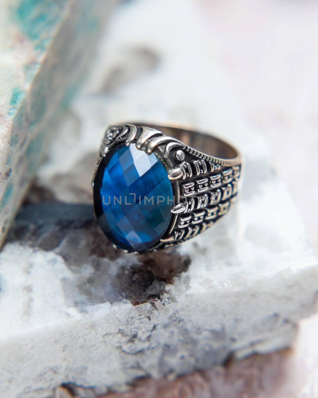 Silver men's ring with blue gem on white marble background