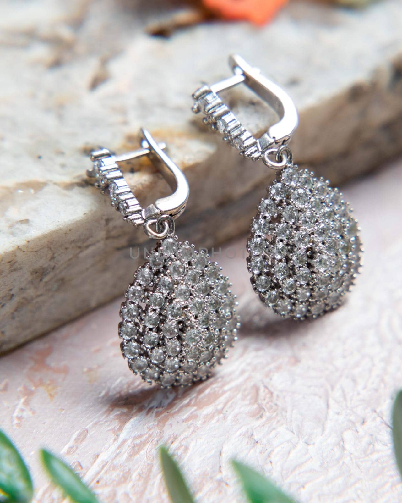 Pair of silver earrings with diamonds lying on stone surface