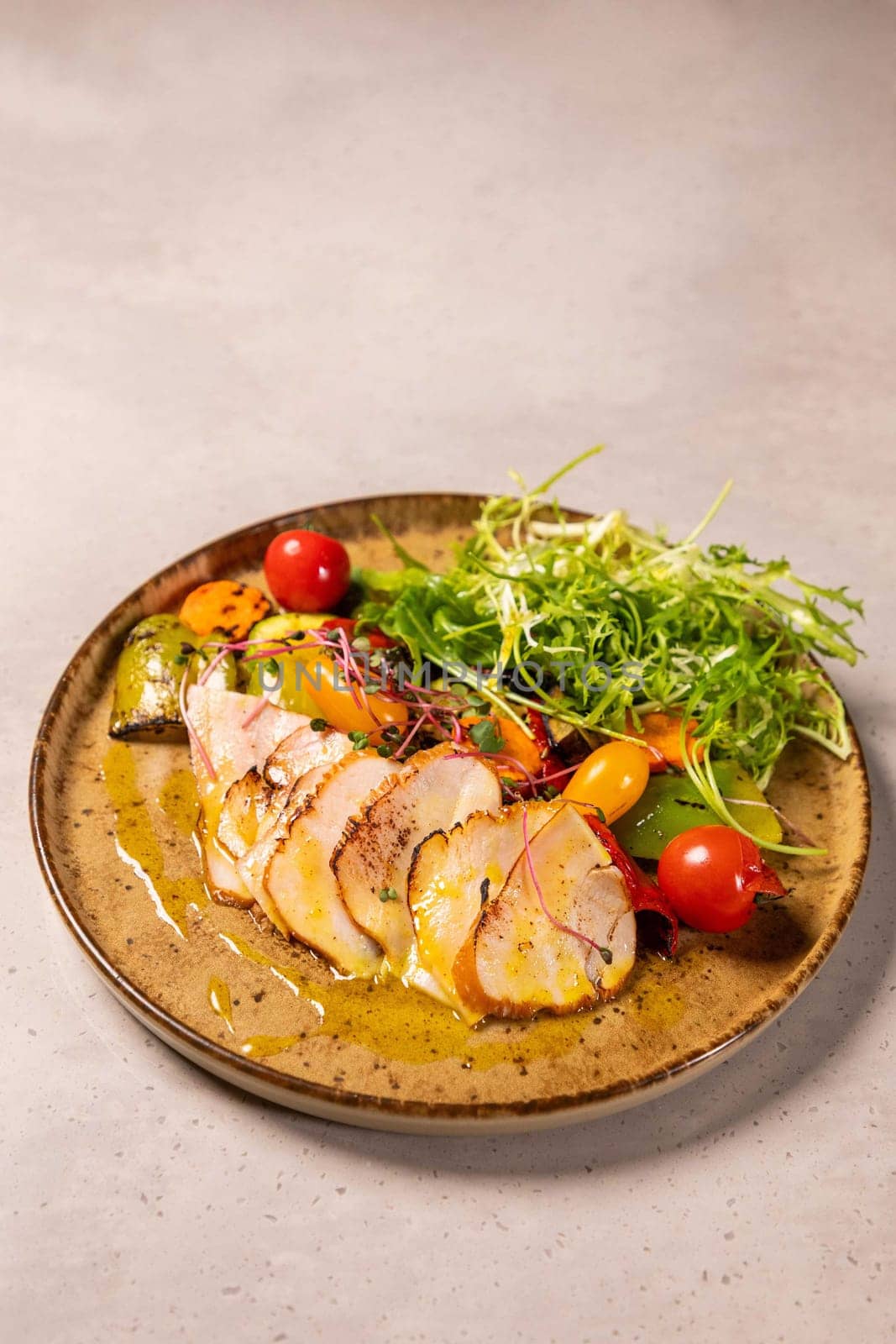 Sliced chicken breast served on a plate with grilled vegetables and mustard sauce