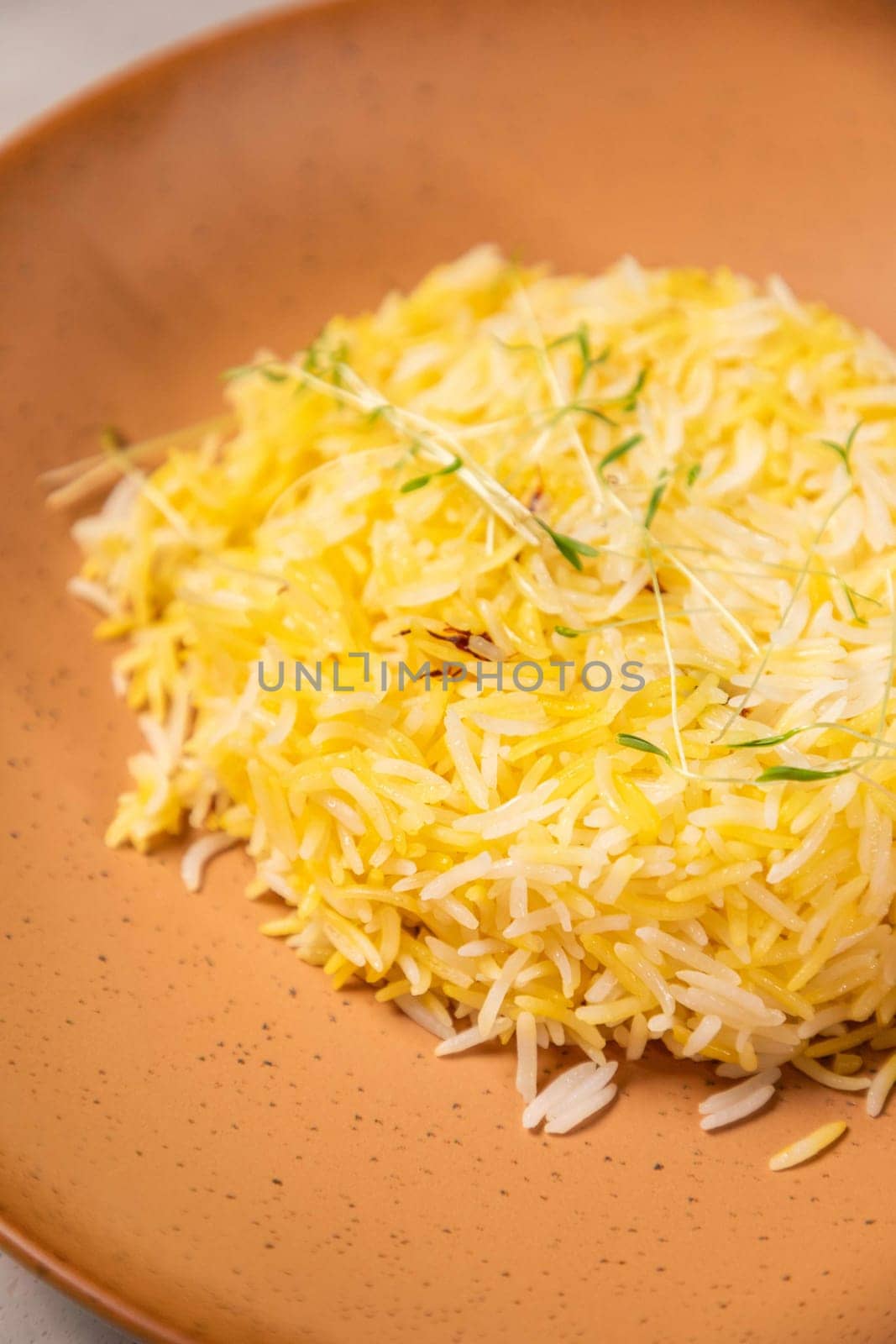 Saffron rice seasoned with saffron threads and sprigs of thyme on a plate