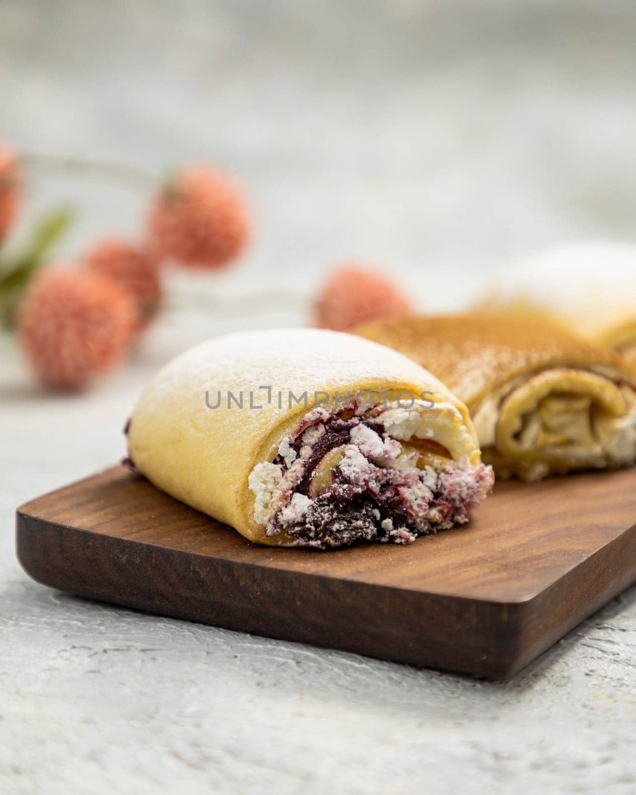 Delicious sweet rolls with berry jam sprinkled with powdered sugar lying on wooden cutting board