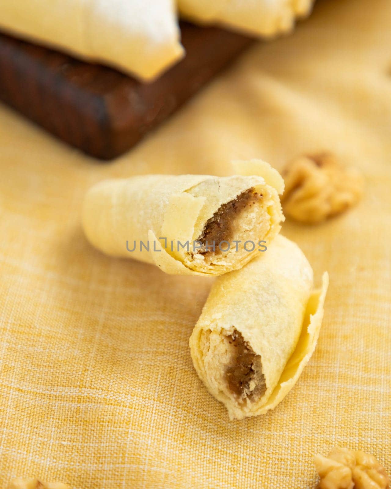 Delicious homemade sweet rolls filled with walnuts lying on the yellow tablecloth