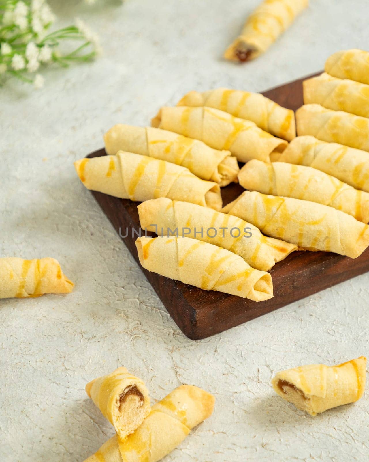 Delicious rugelach pastries with a sweet filling drizzled with sugar glaze are lying on a wooden board