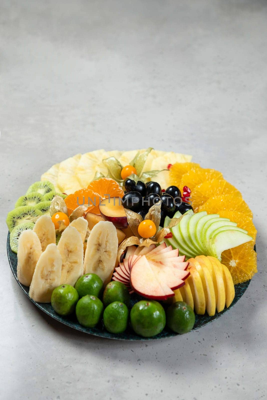 Colorful variety of sliced fruits are arranged on a plate, creating an appetizing display of healthy eating options