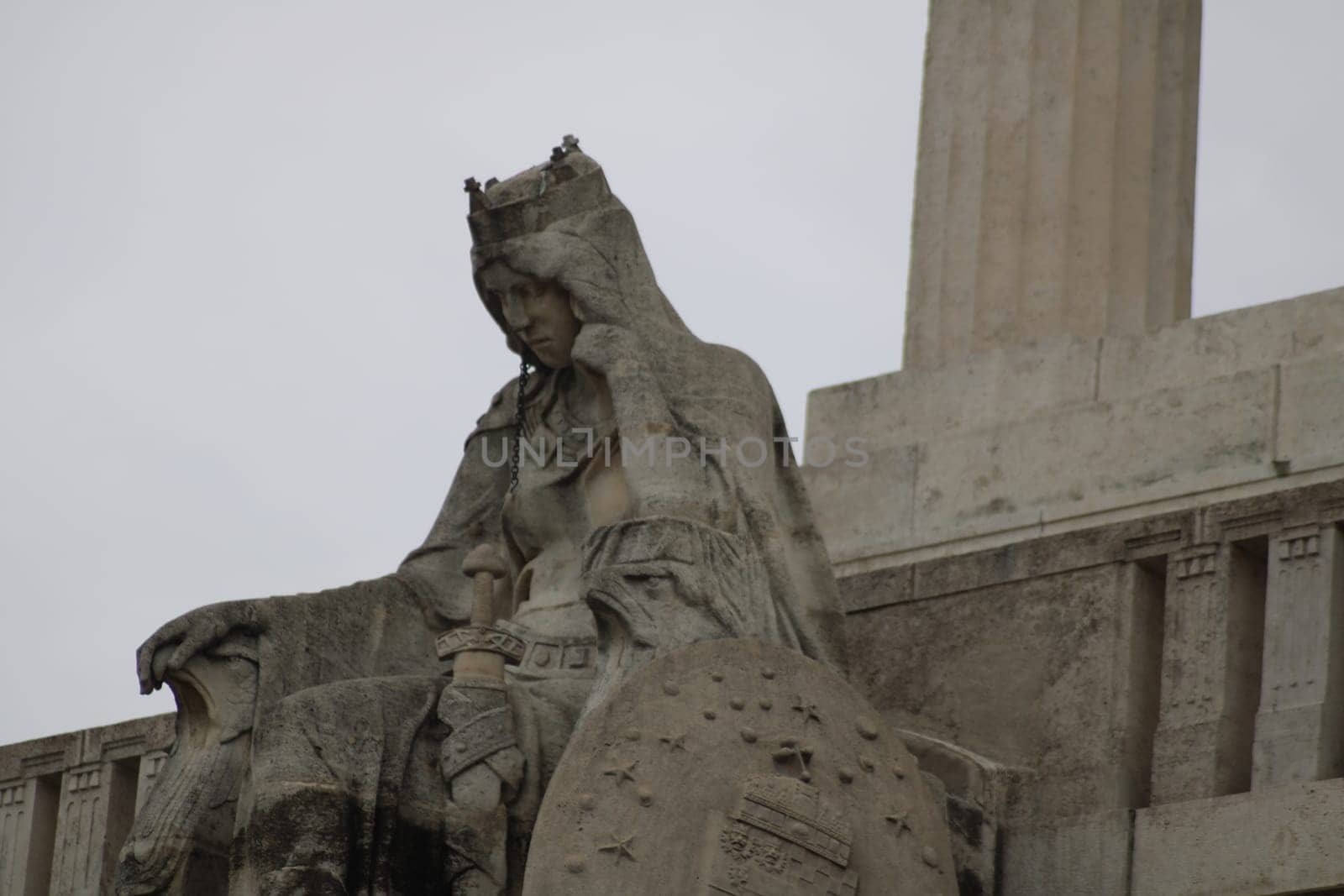 A large statue depicts a regal figure lost in thought, featuring detailed artistry and symbolic elements, prominently displayed in a well-known city square, inviting reflection.