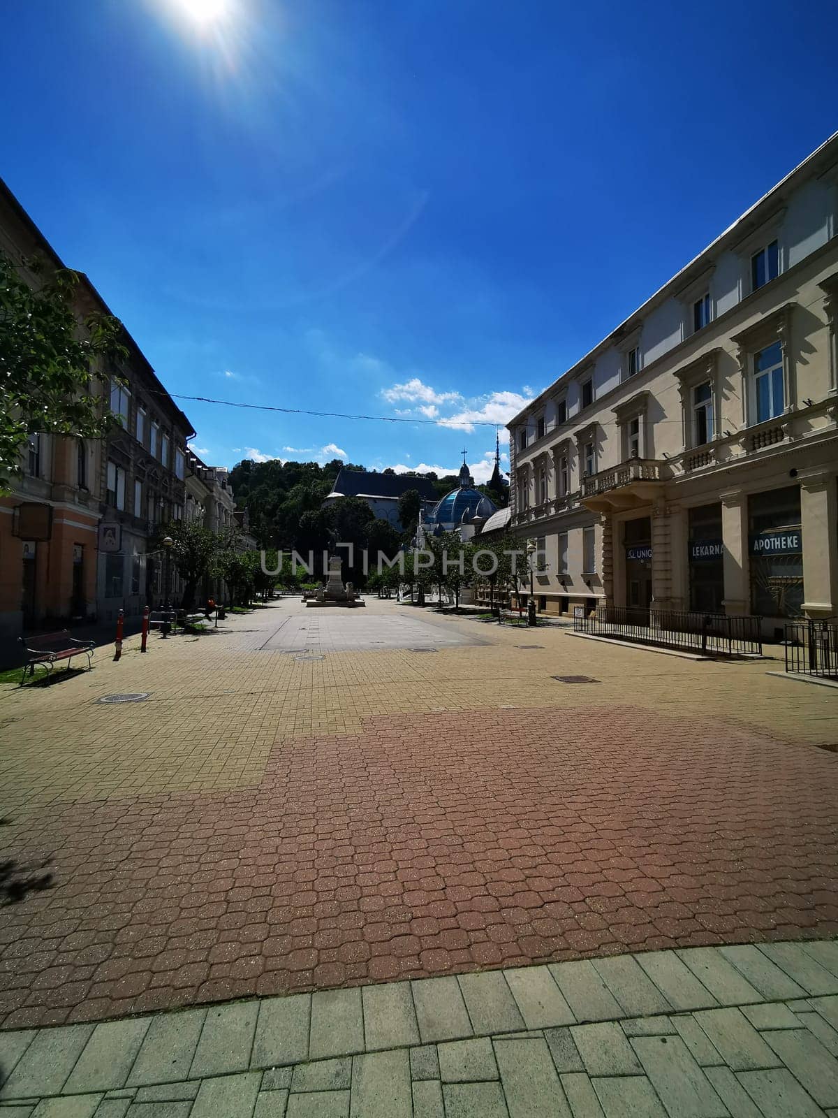 A peaceful street lined with trees and old buildings offers a tranquil atmosphere on a sunny afternoon, inviting leisurely strolls and exploration.
