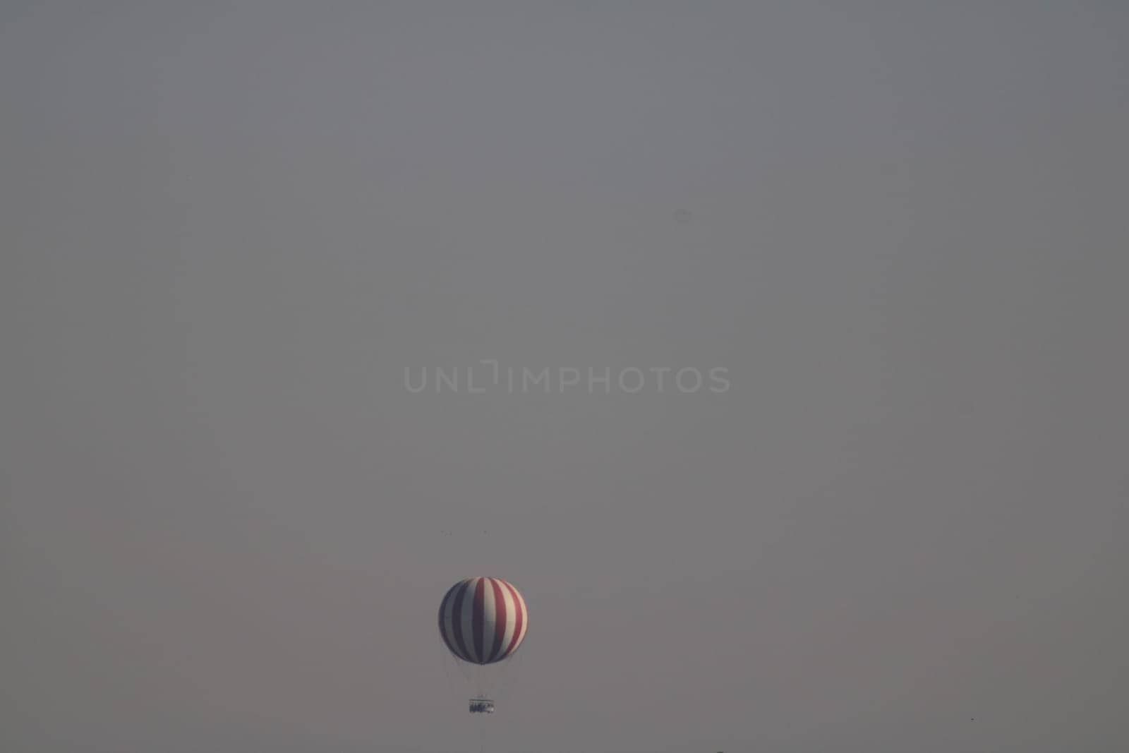 A vibrant hot air balloon ascends gracefully into the clear skies at dawn, casting a calm silhouette against the pastel colors of the horizon.