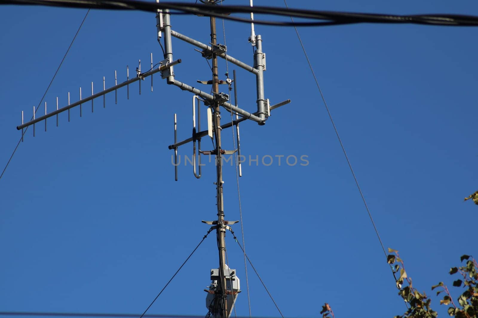 Tall communication tower equipped with multiple antennas reaches towards a bright blue sky, emphasizing its role in urban connectivity and telecommunications.