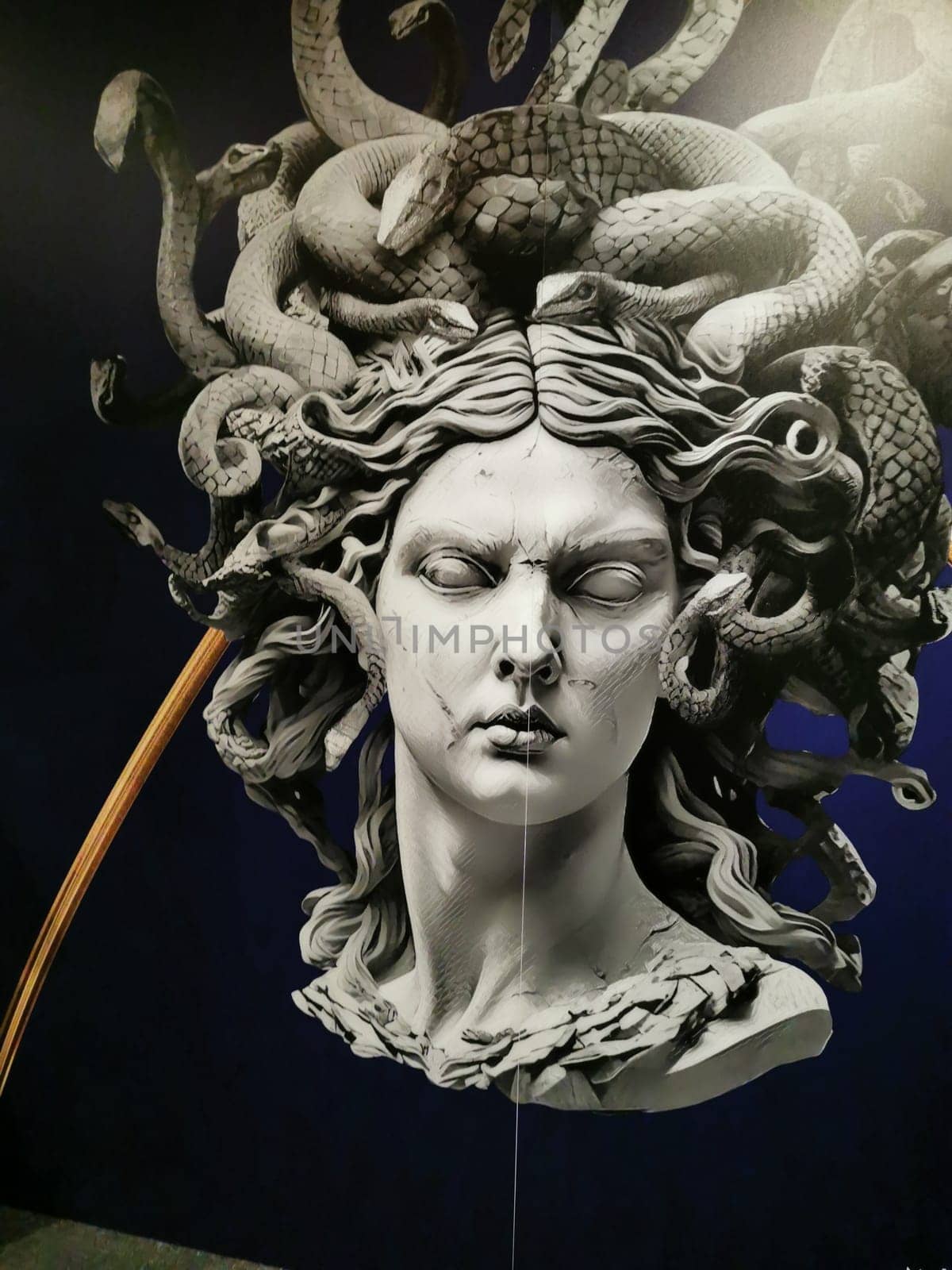 A striking depiction of Medusa features her snake hair and intense facial expression, prominently displayed in an art exhibition, highlighting the detailed craftsmanship.