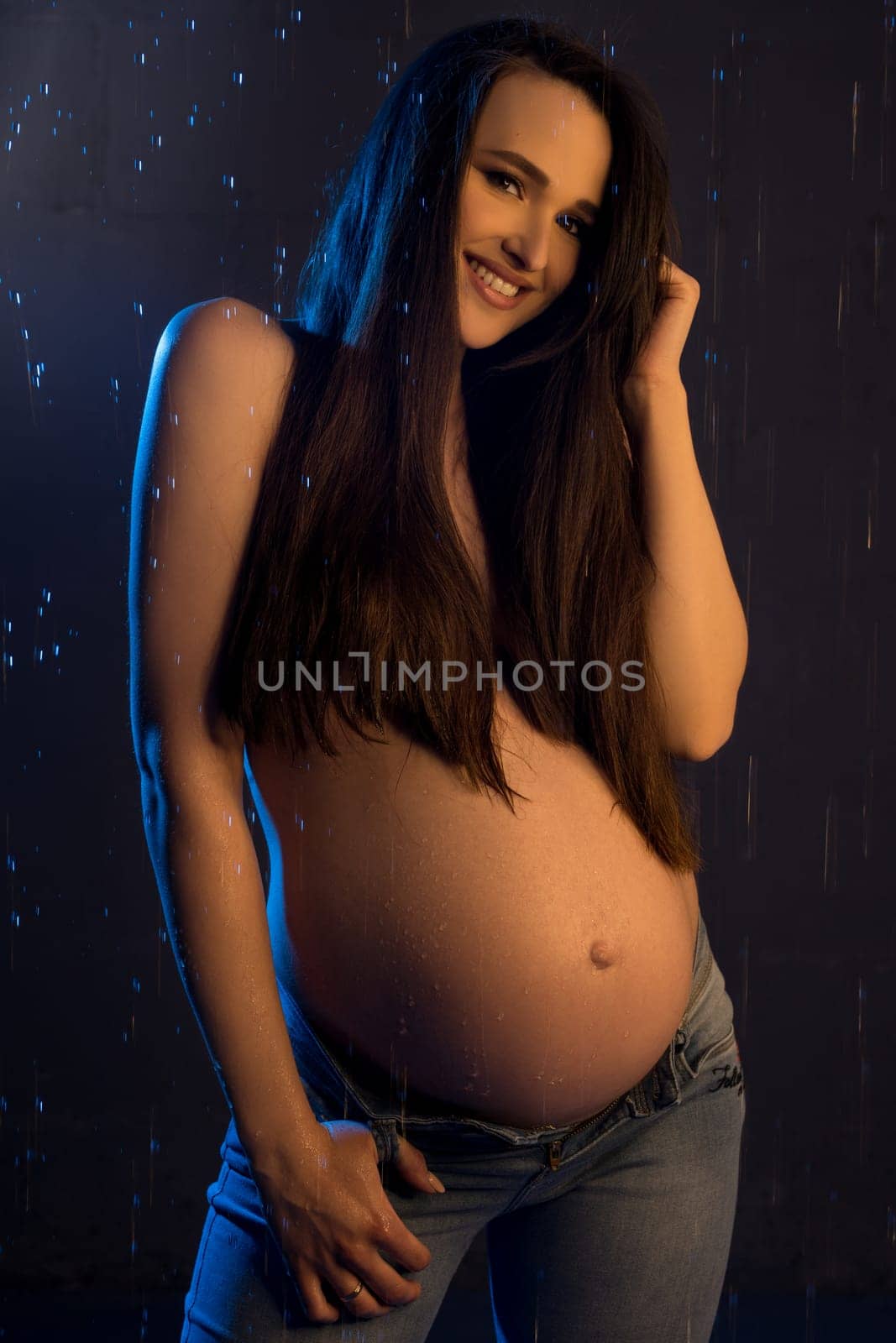 Gorgeous pregnant brunette wearing only jeans cropped topless view
