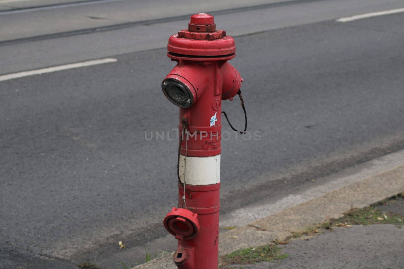 A prominently displayed red fire hydrant is positioned on the sidewalk beside a quiet street, prepared for potential fire emergencies in the daylight.