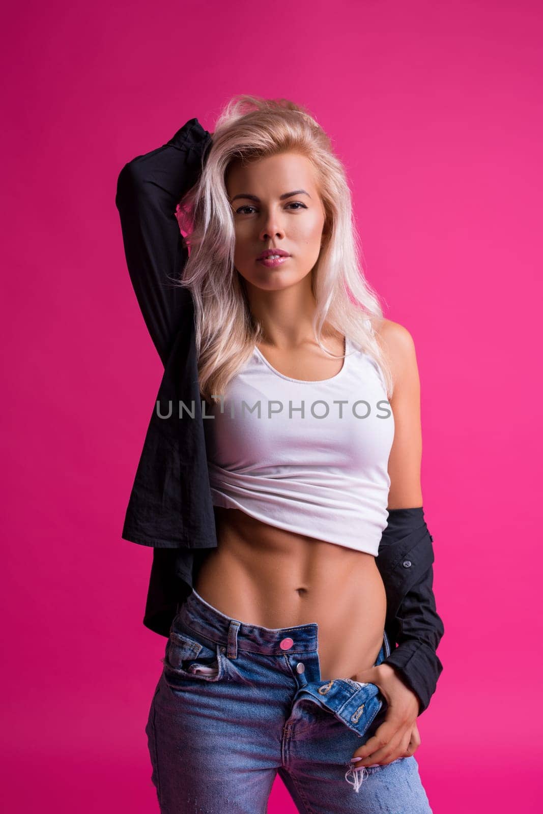 Sexy blonde in jeans and top cropped shot against pink background