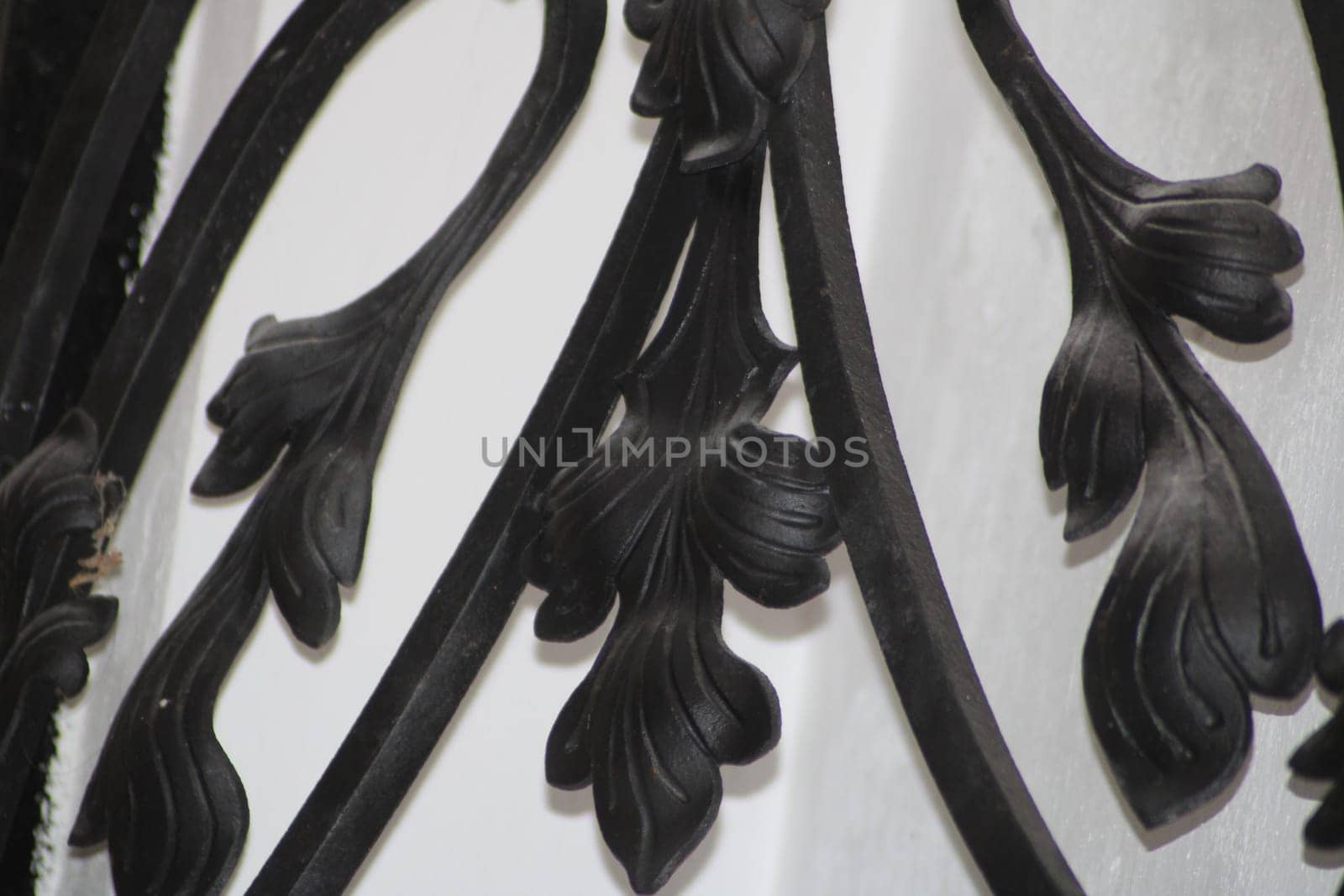 Intricate floral patterns in black metal are showcased against a white background, highlighting craftsmanship and design details in the bright light.
