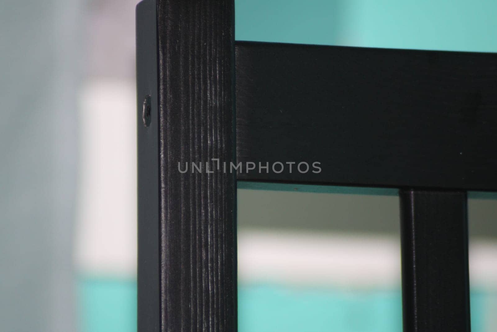 The black wooden chair leg captures attention with its sleek finish and craftsmanship while contrasting against a bright turquoise background setting.
