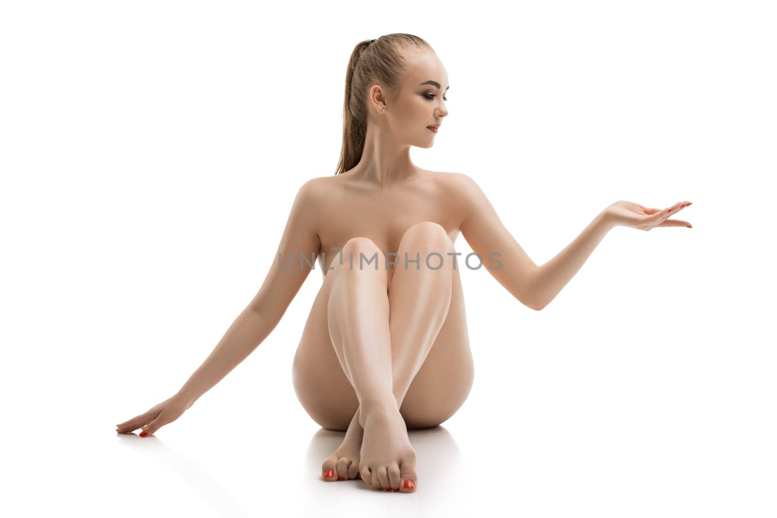 Nude graceful blonde sitting alone on the floor isolated shot