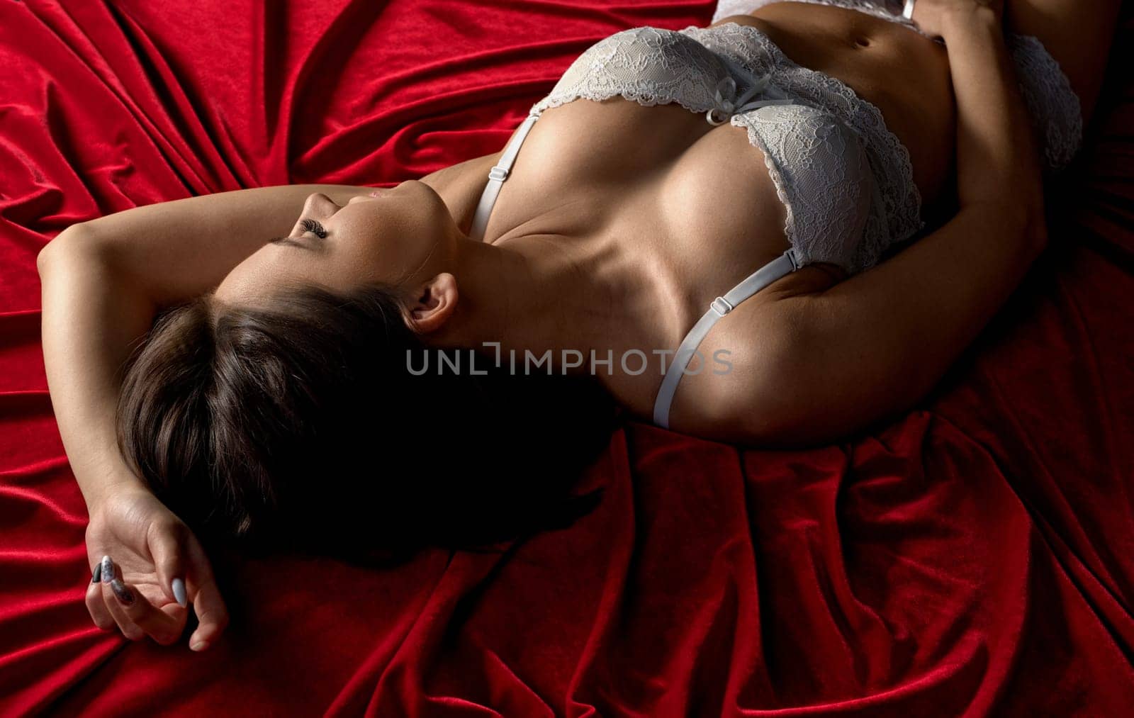Woman in lace lingerie experiencing a pleasurable moment lying in bed high angle shot