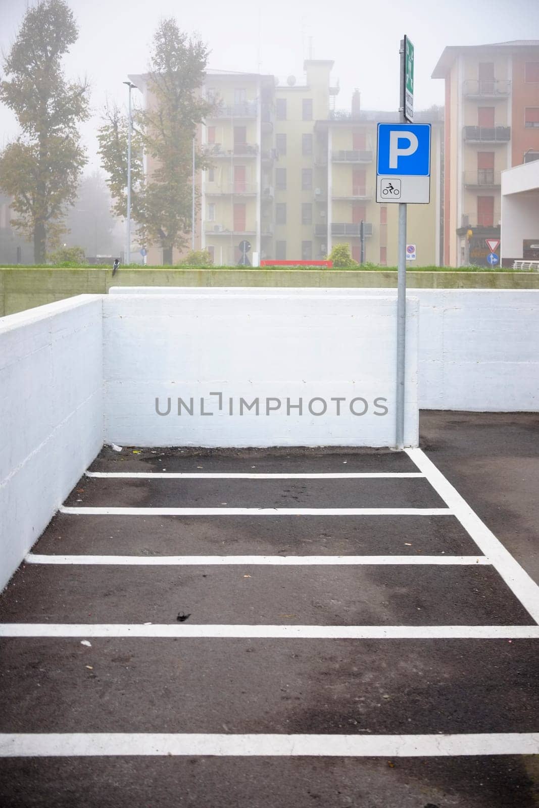 Cremona, Lombardy, Italy - November 7th 2024 Motorcycle parking spot with white lines and sign indicating parking for motorcycles only, located in a foggy city on an overcast day