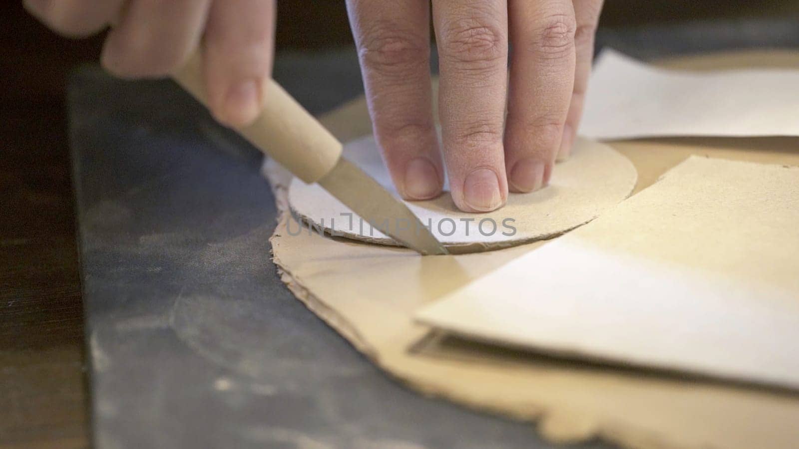 An artisan skillfully and carefully shapes intricate leather patterns by using precise cutting tools with ease. Stock Clip