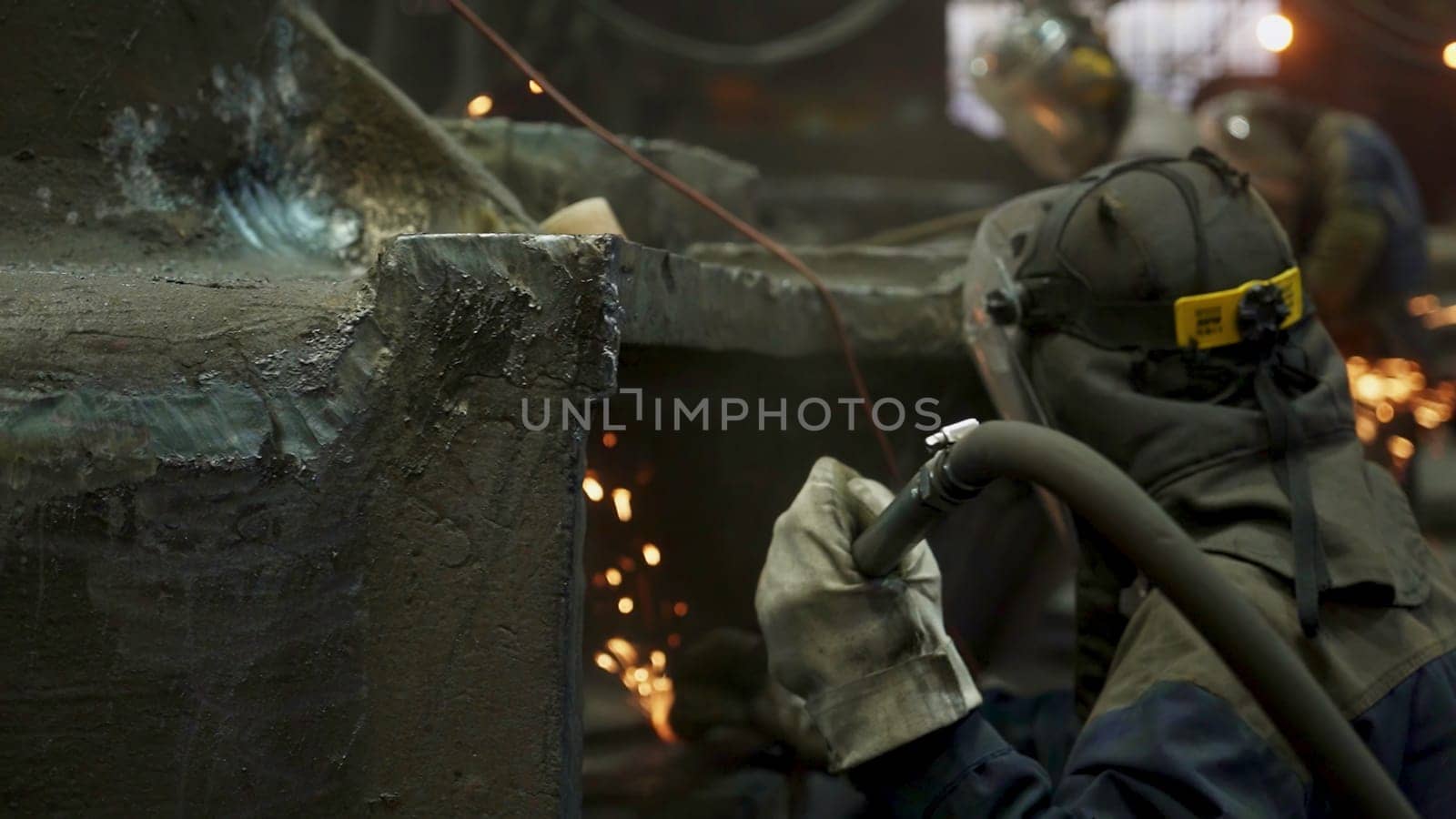 Dedicated workers are engaged in welding, skillfully creating vibrant sparks in a busy industrial environment. Stock Clip