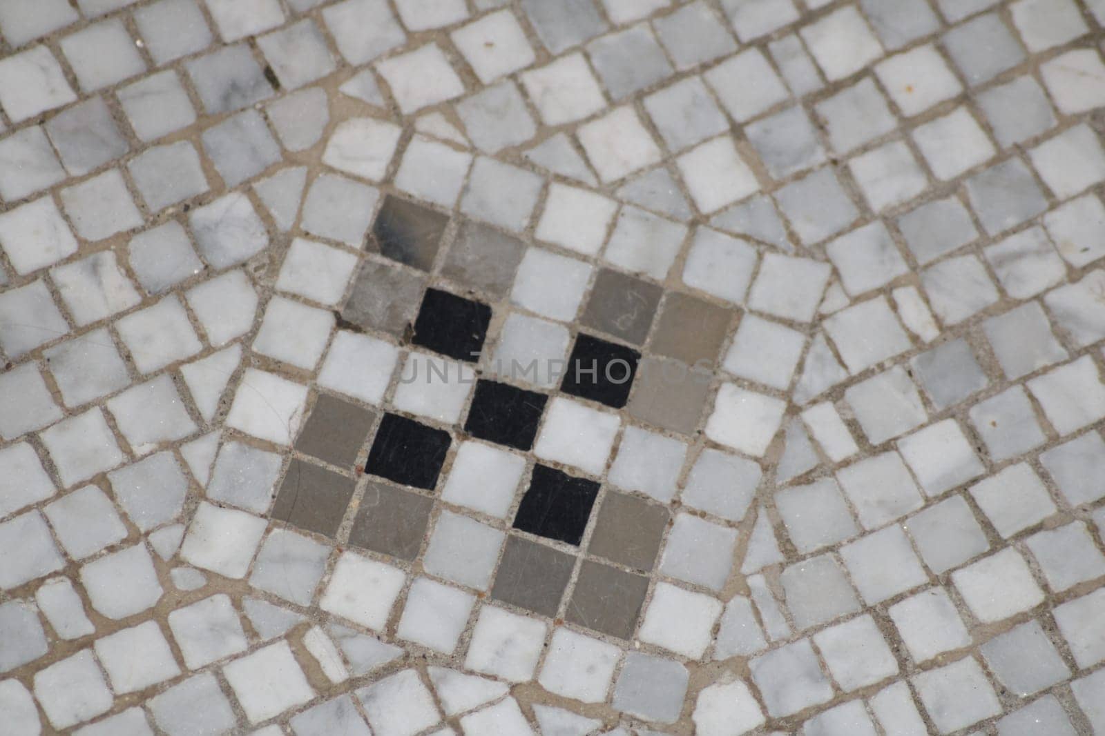 A distinct mosaic tile arrangement showcases a geometric design composed of gray and black tiles. This decorative flooring reflects traditional craftsmanship, typical in historic locations.