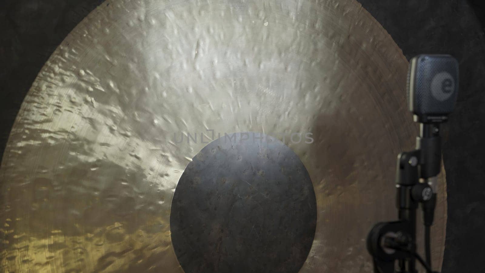 A beautifully designed golden gong set for sound recording, with a microphone capturing its rich resonance. Clip