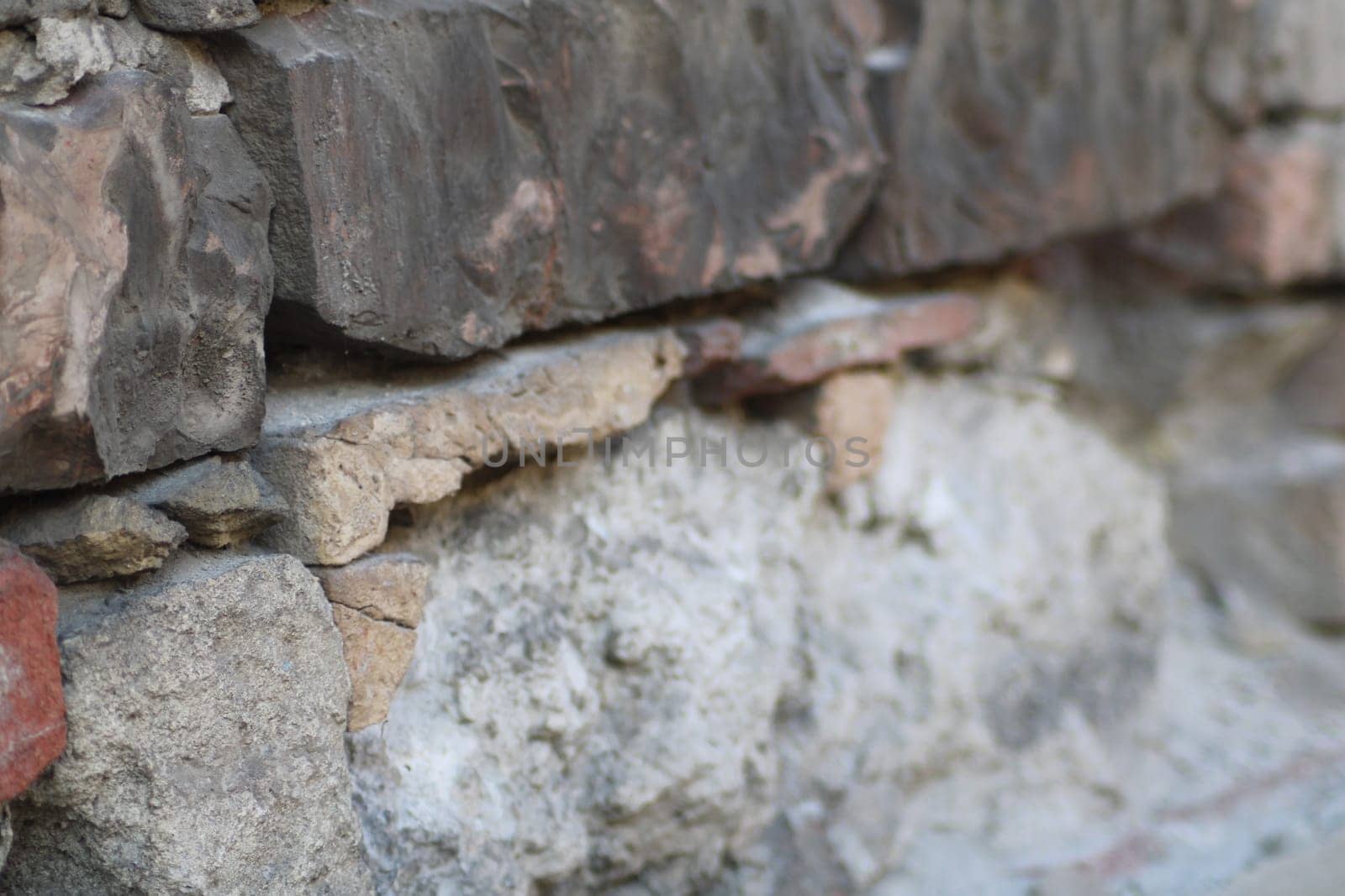 The wall features a variety of stones, showcasing different colors and textures, with visible signs of weathering under the warm afternoon light.