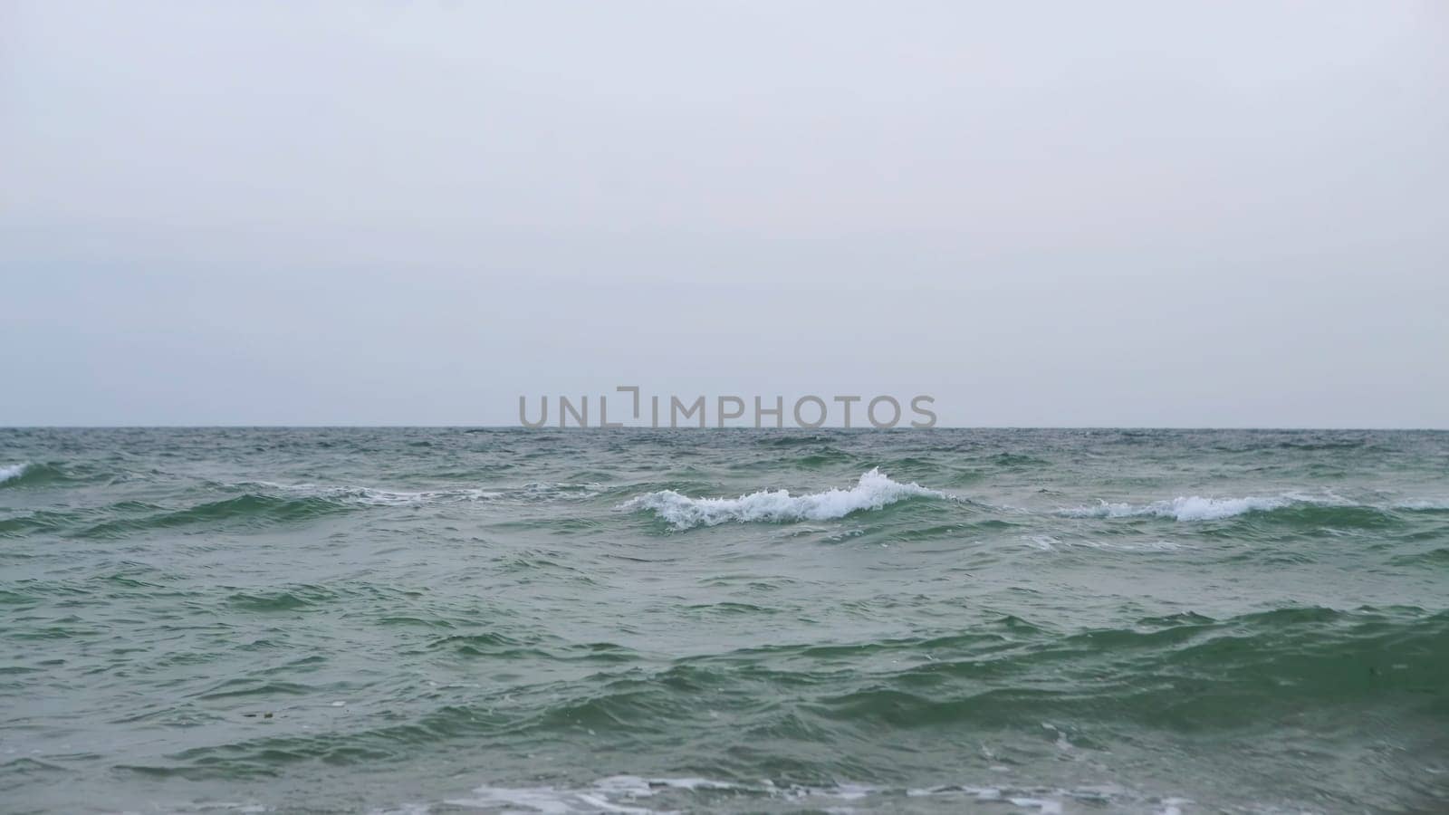 A wonderfully serene view of the ocean waves gently merging with a soft gray sky, evoking deep tranquility and peace