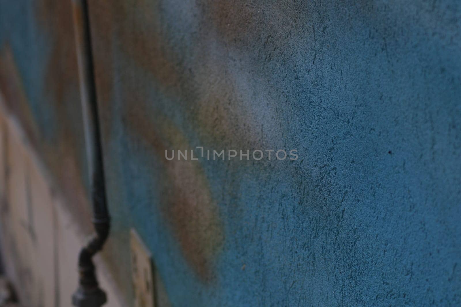 A textured blue wall features a colorful urban mural detail, highlighting the artistic expression found in a lively city. The scene reflects urban culture.