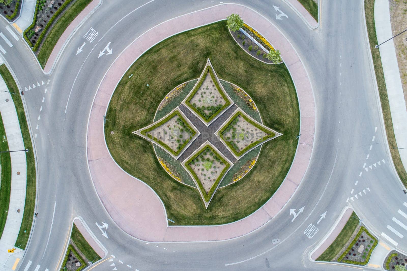 A round intersection with a grassy area in the middle. The grass is trimmed and the area is surrounded by a brick wall