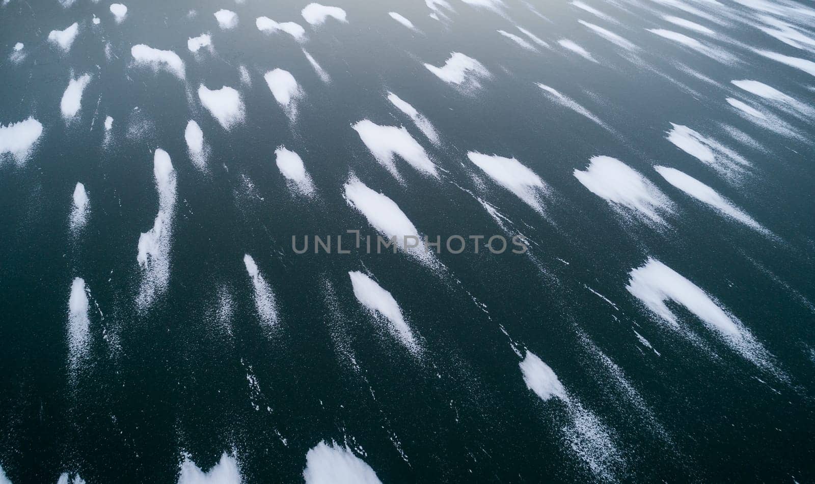 A body of water with a lot of snow on it. The snow is scattered all over the water, creating a beautiful and serene scene. Scene is peaceful and calm, as the snow covers the water